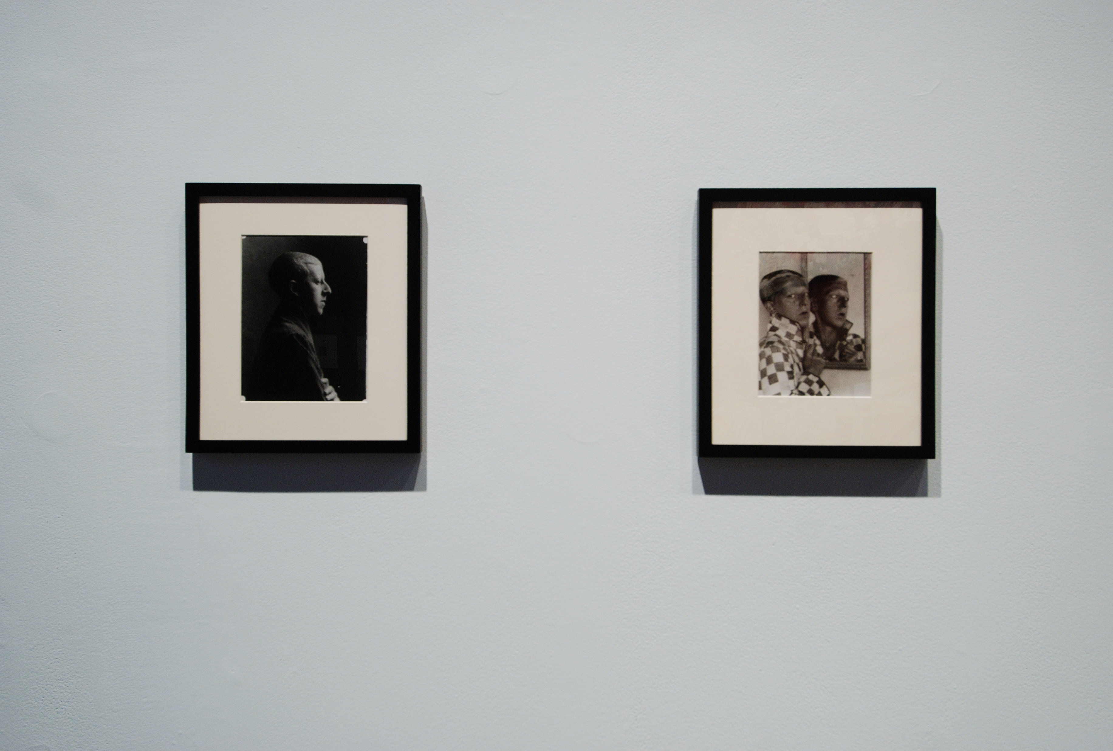 Two black and white photos, a dimly lit side profile portrait and a person posing in a checkered jacket in front of a mirror.
