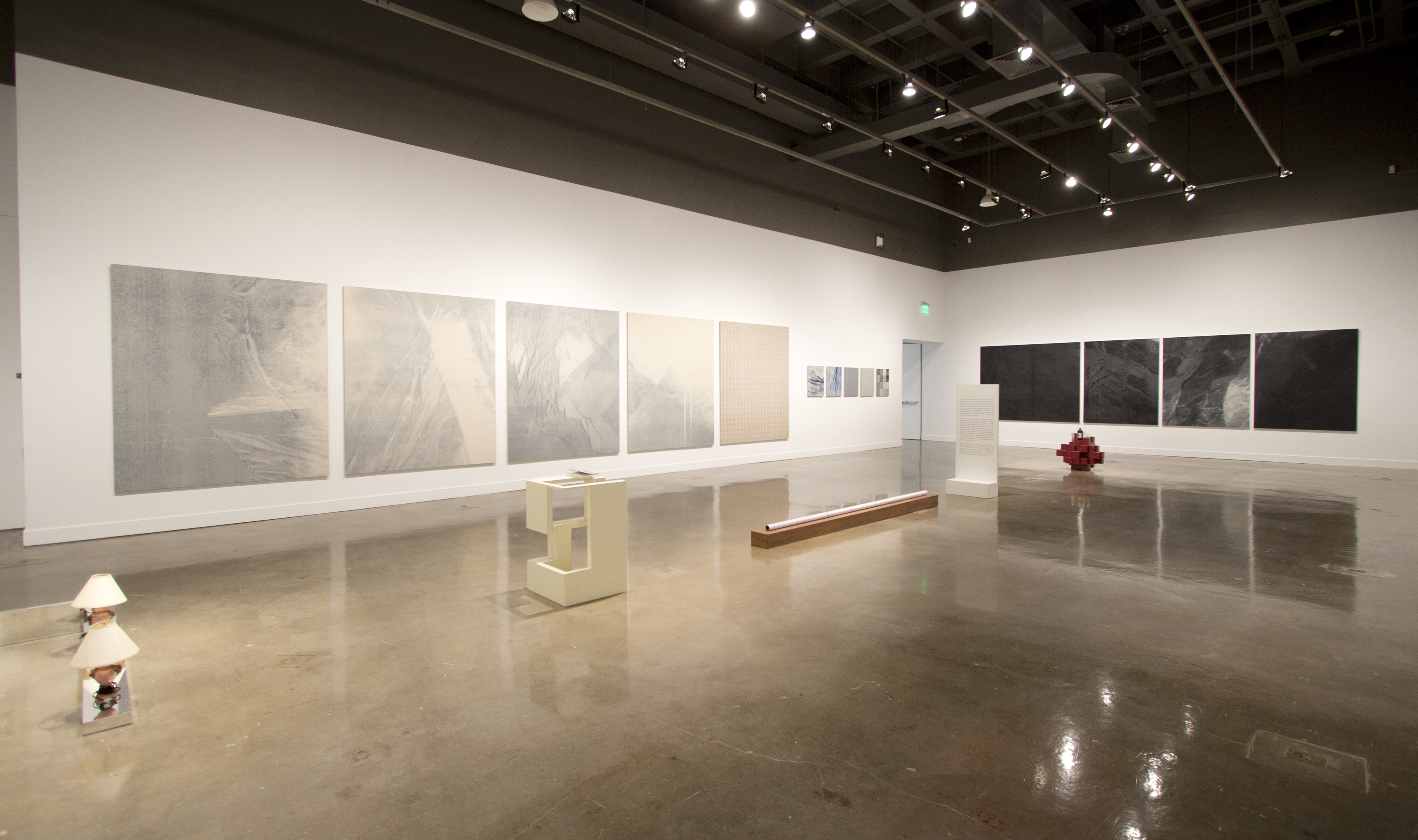 Corner shot of gallery with 2 mulit paneled paintings flanking each wall.