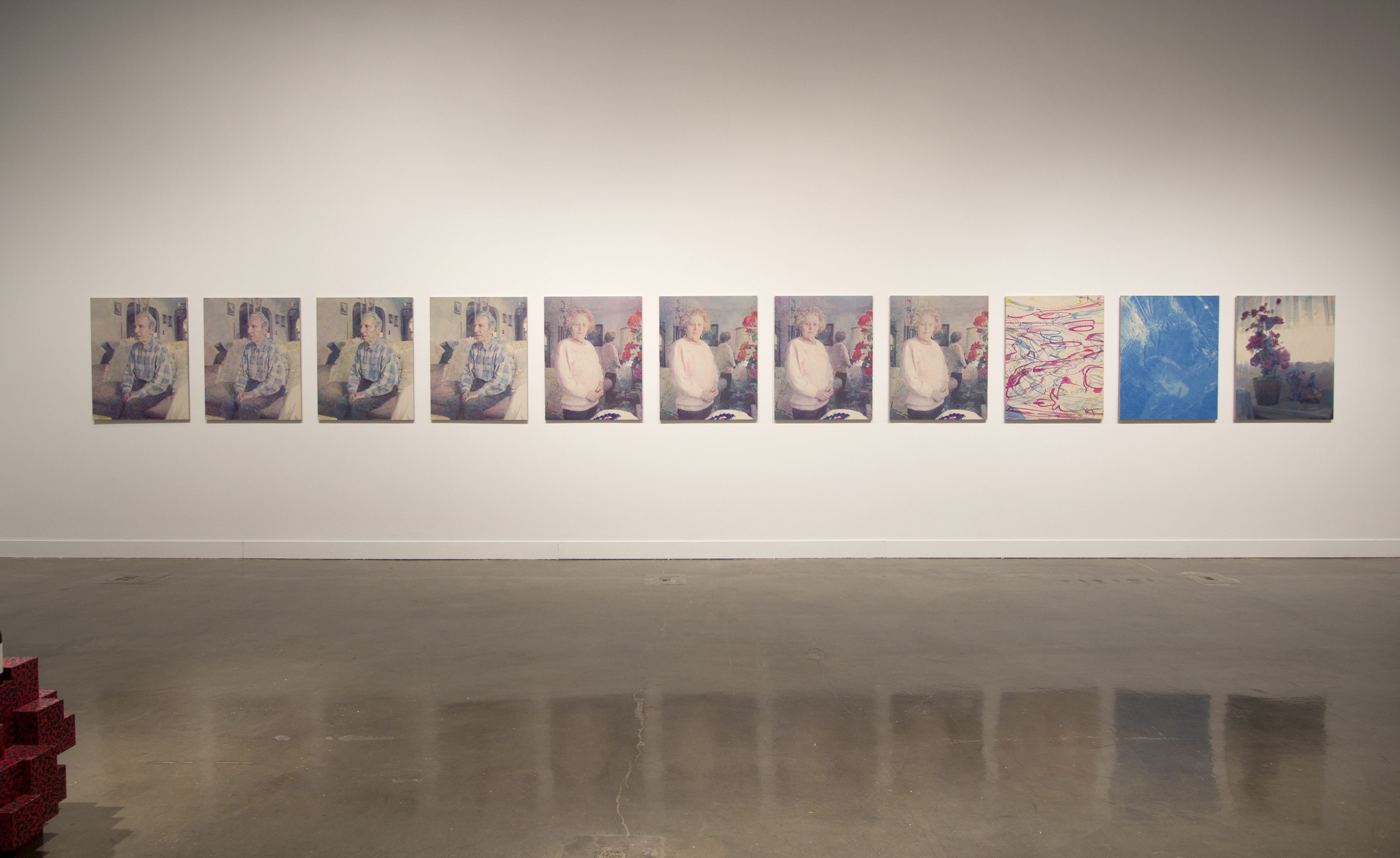 View of gallery with one wall depicting a series of paintings of a person from far away.