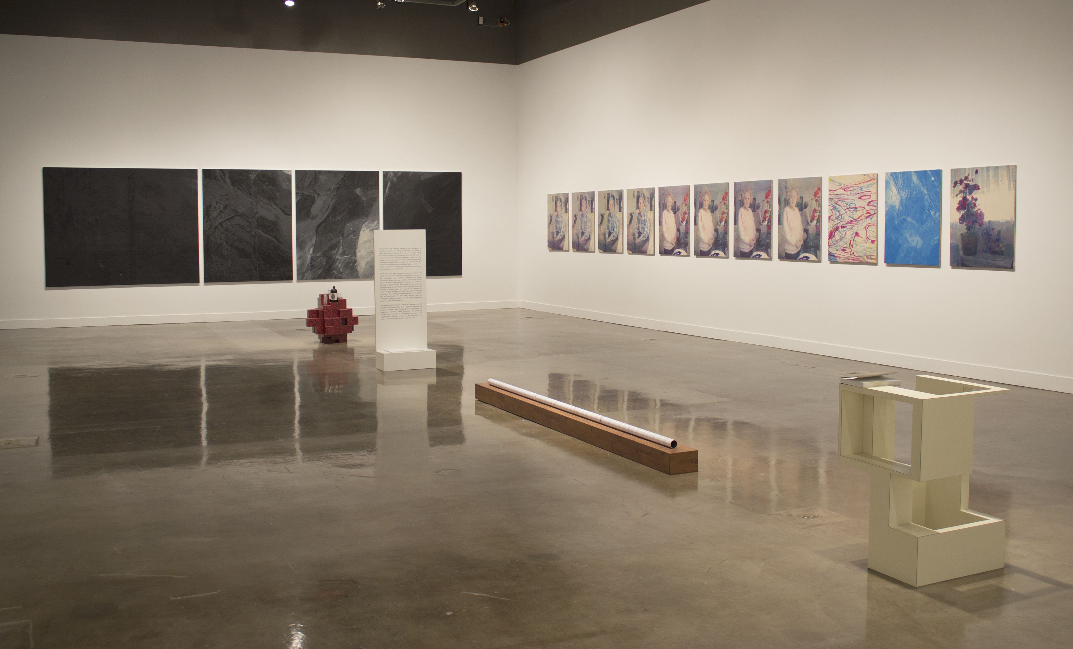 Corner shot of gallery with 2 mulit paneled paintings flanking each wall.