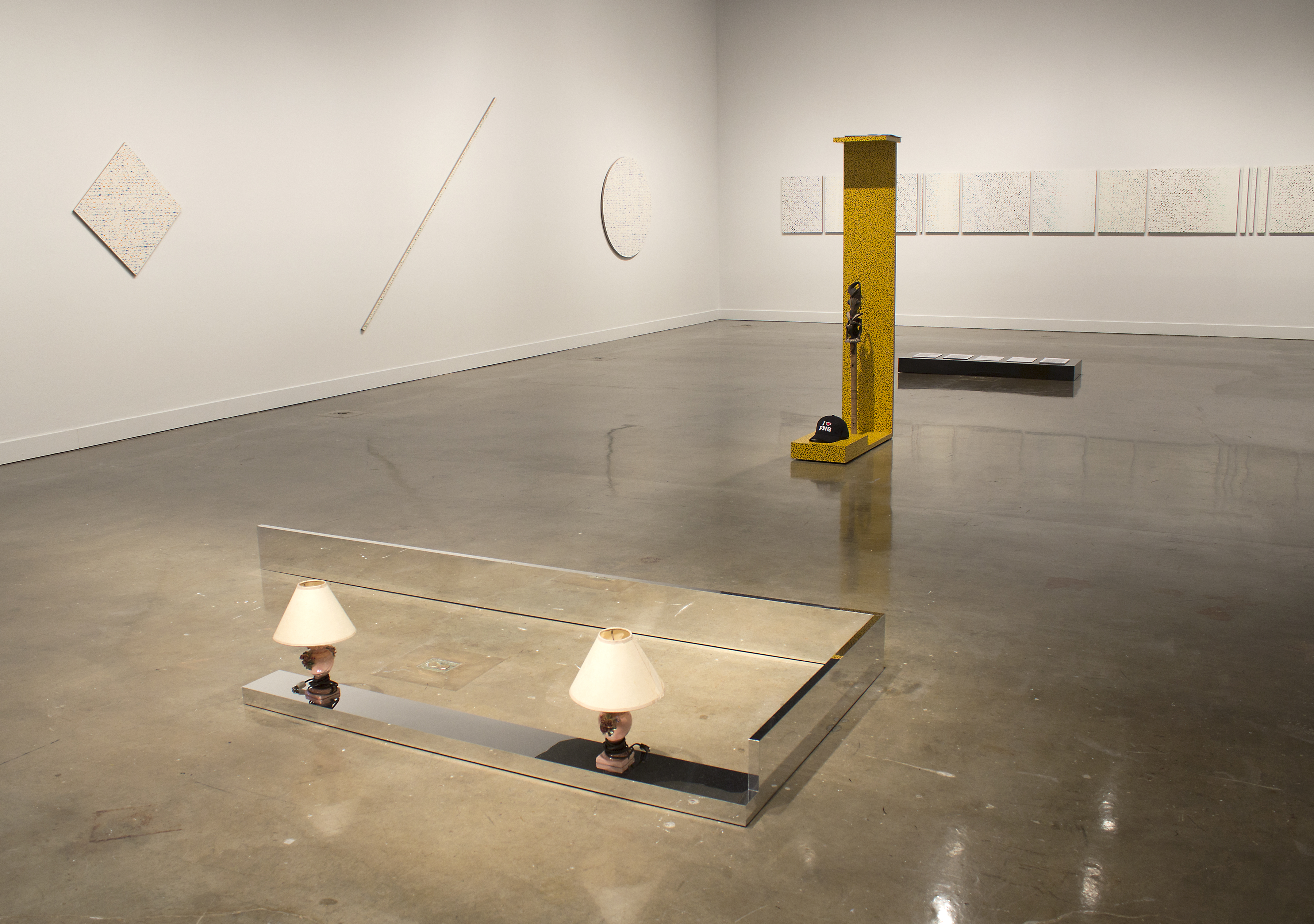 Yellow and black polk dot sculptural that stands 6' tall with smaller floor works in front.