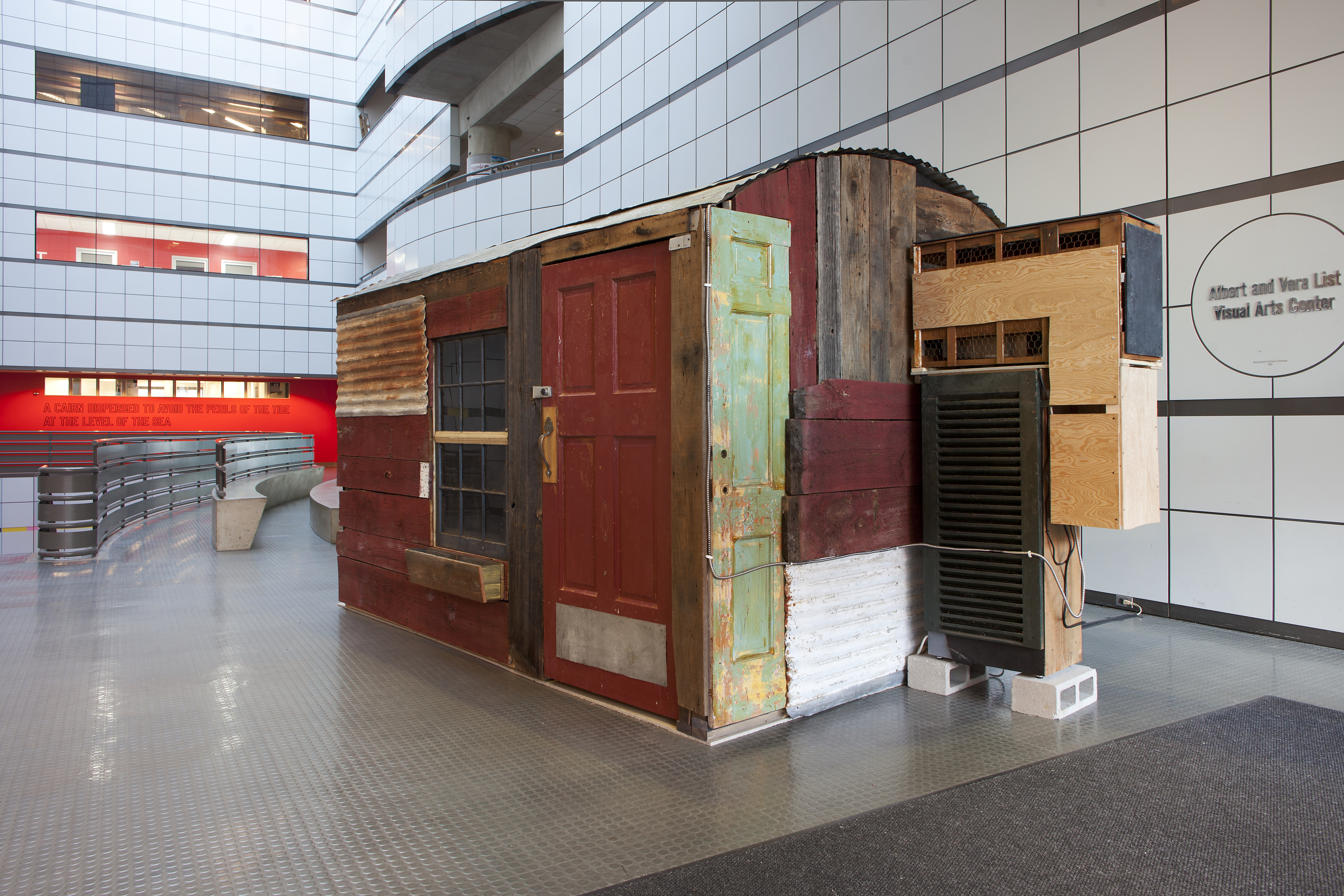 In the middle of the Atrium sits a scrappy cabin made of wood, painted doors, a window, and an addition off the side