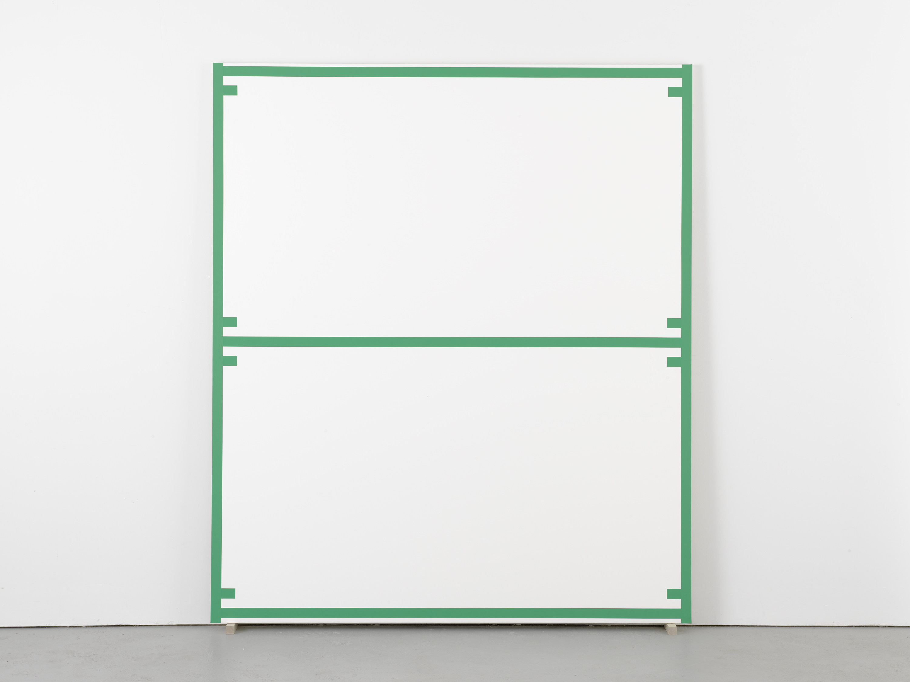 Large canvas edged and bisected with a uniform green line, as well as 8 evenly spaced short lines, leans against a wall.