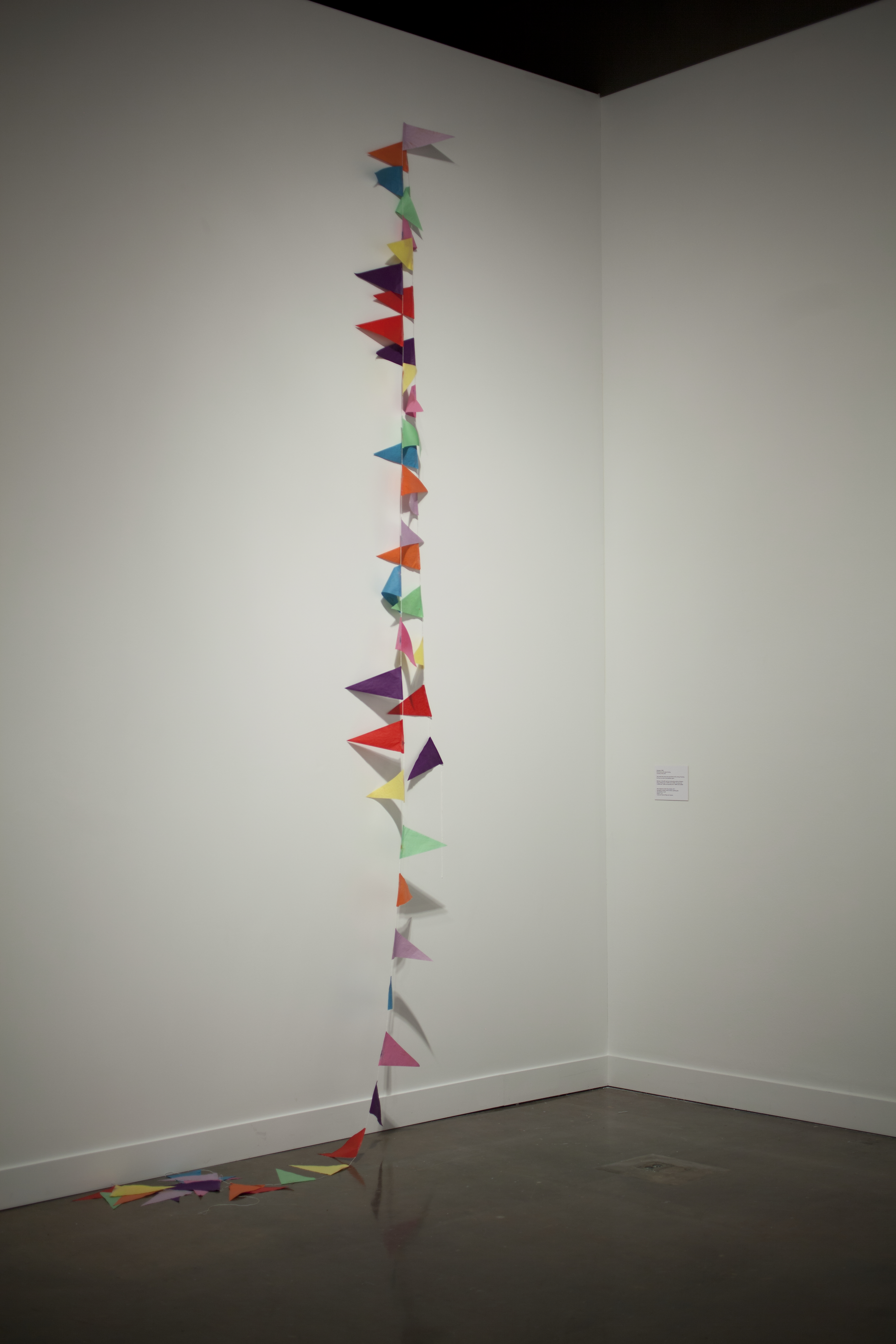 A colorful string of banners hangs down from top of a wall and drapes onto the floor.