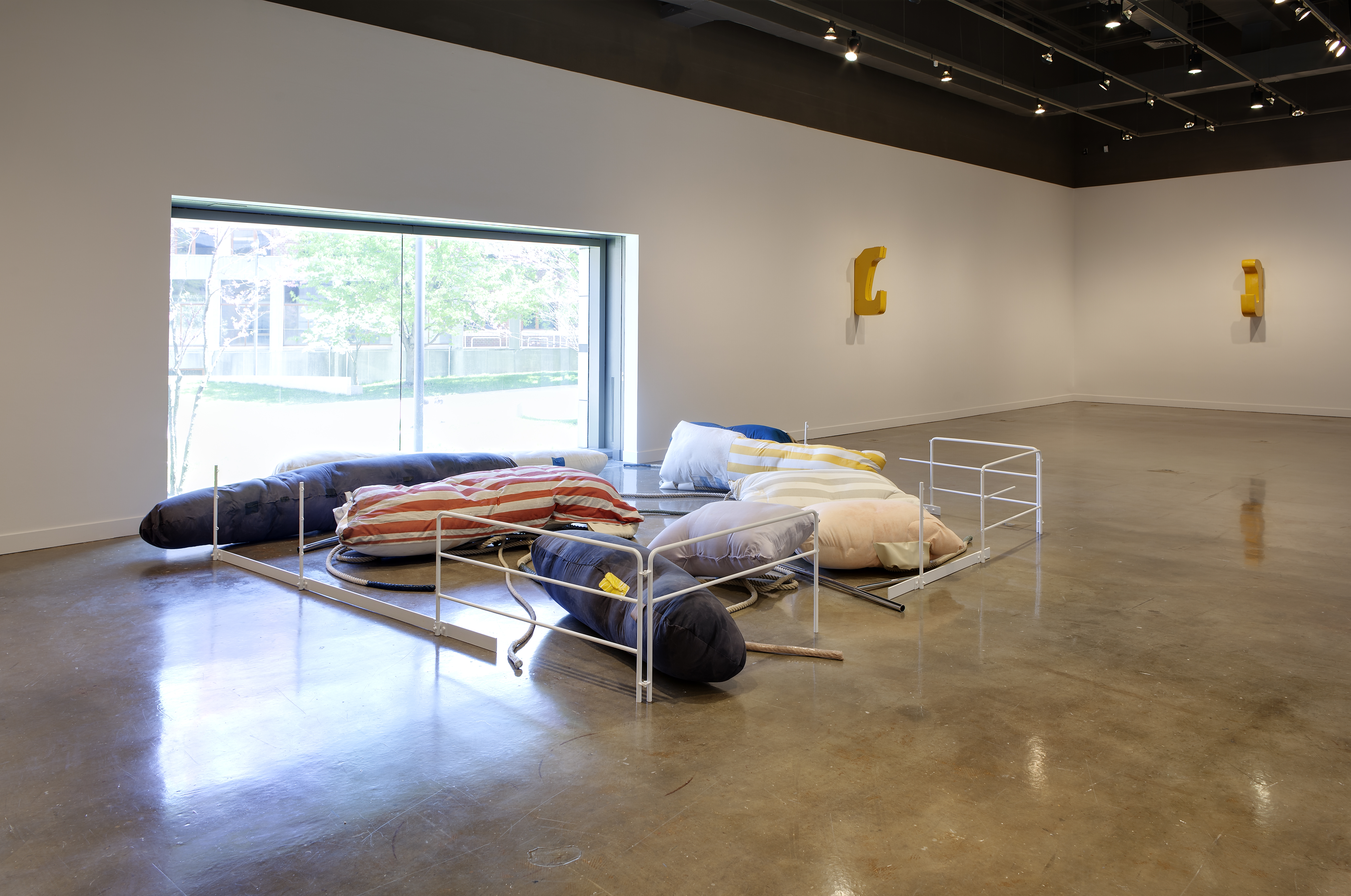 Large pillows of various sizes and colors arranged in front of a large picture window, surrounded on 3 sides by white gates.