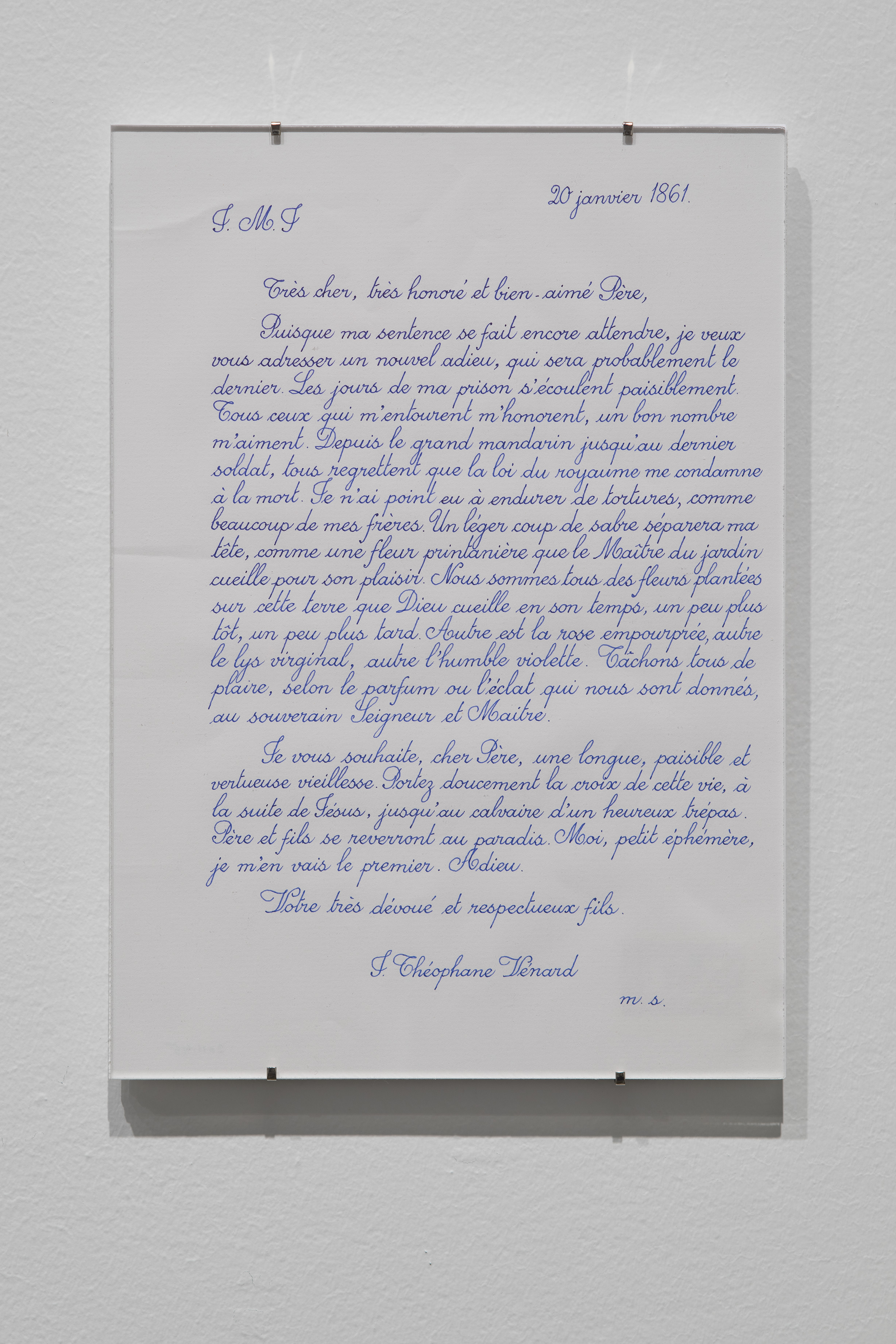 Written in French with blue ink, a document clipped behind glass and dated “20 janvier 1861” hangs on a white wall