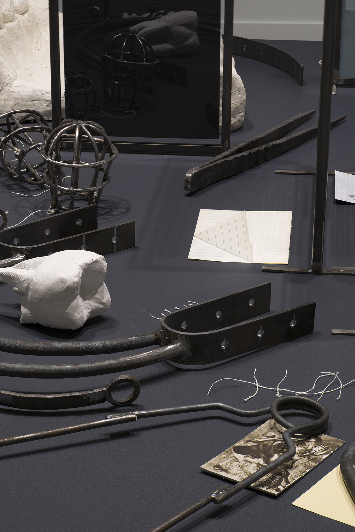 Collection of metal and plaster objects, including a cast of a tooth, as well as white string and glass picture frames.
