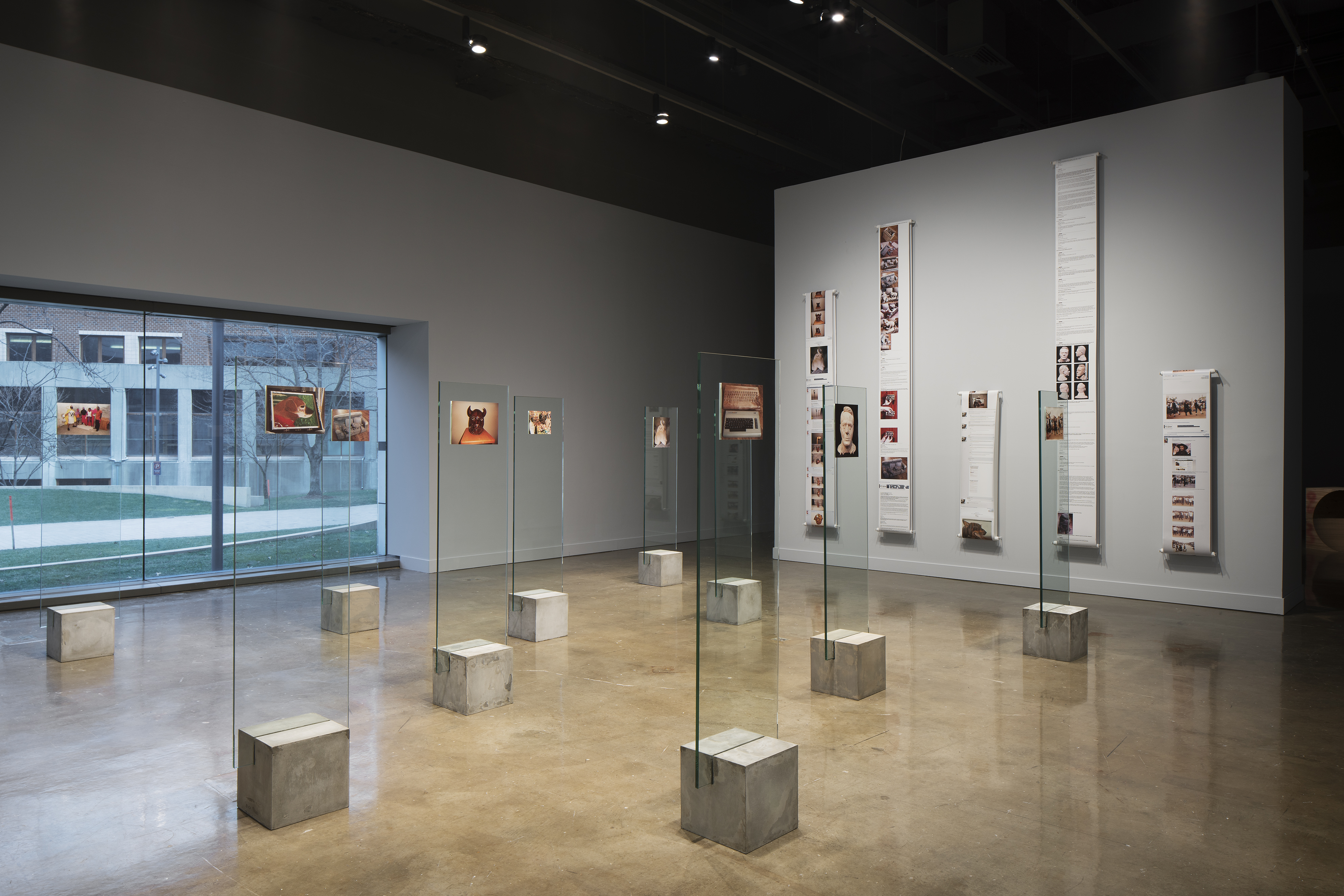 Glass slabs sit atop concrete pedestals with images adhered to the tops.