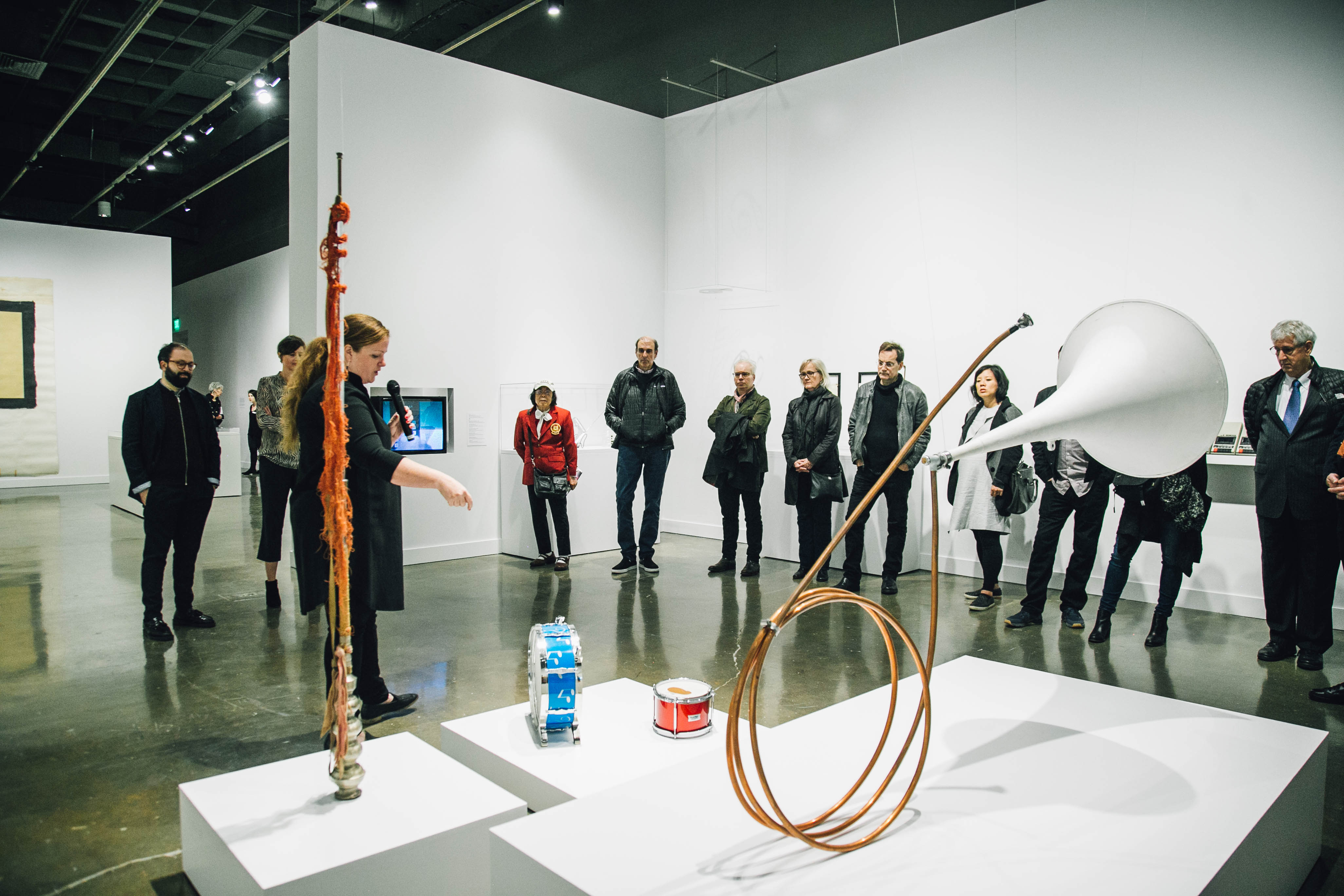 A gallery guide points to sculptures by Tony Conrad and engage a group of gallery visitors.