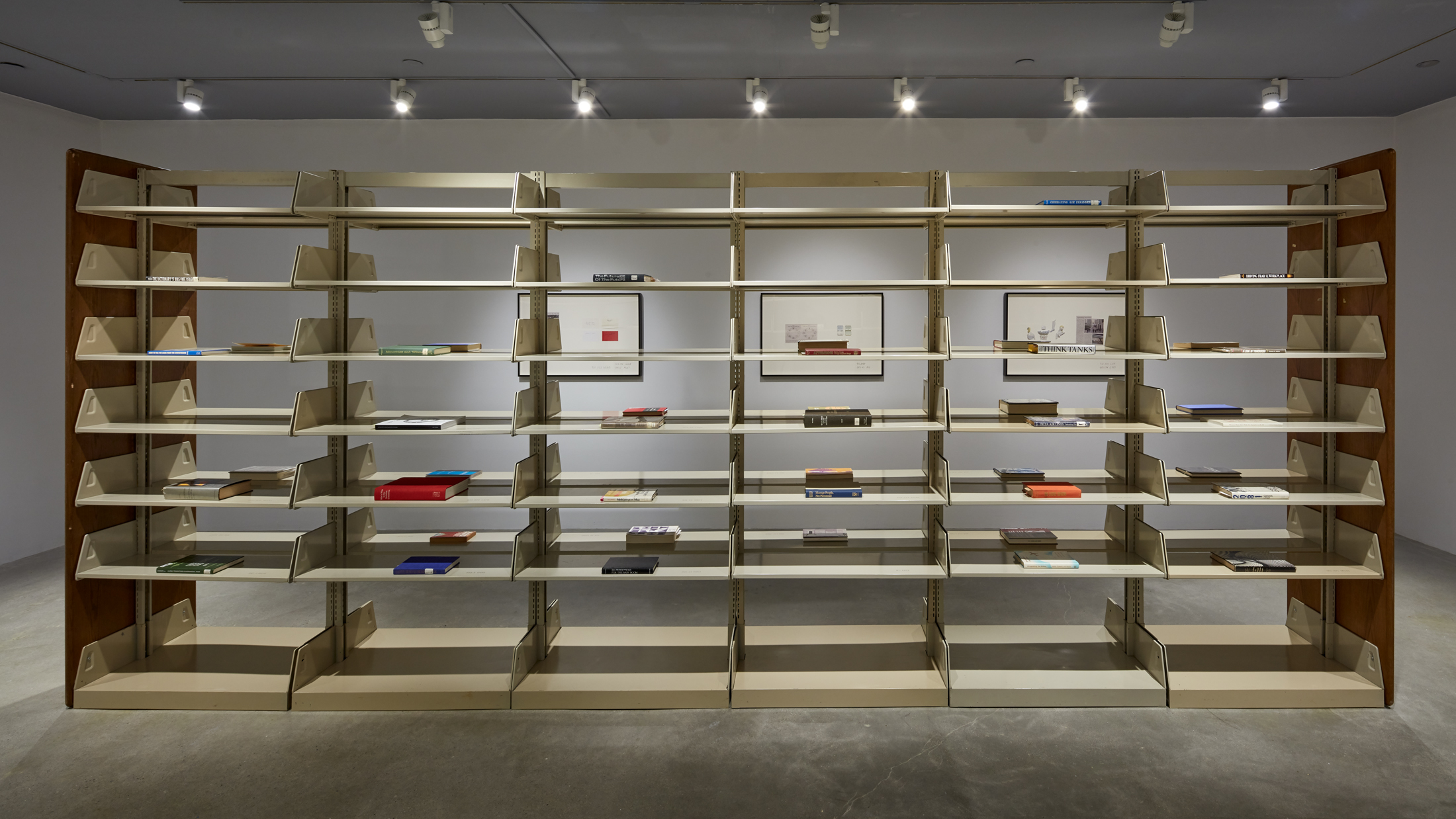 A large wooden shelving unit sculpture is featured in a gallery space.