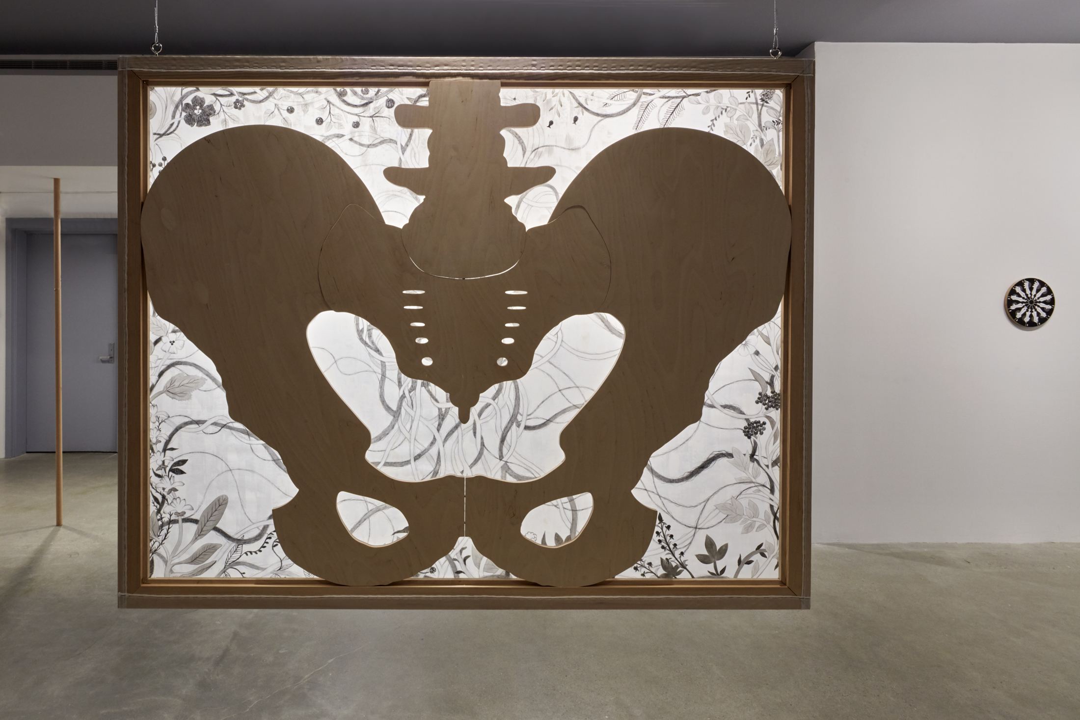 Backside of the hanging painting with the cutout wooden shape of a pelvic bone.