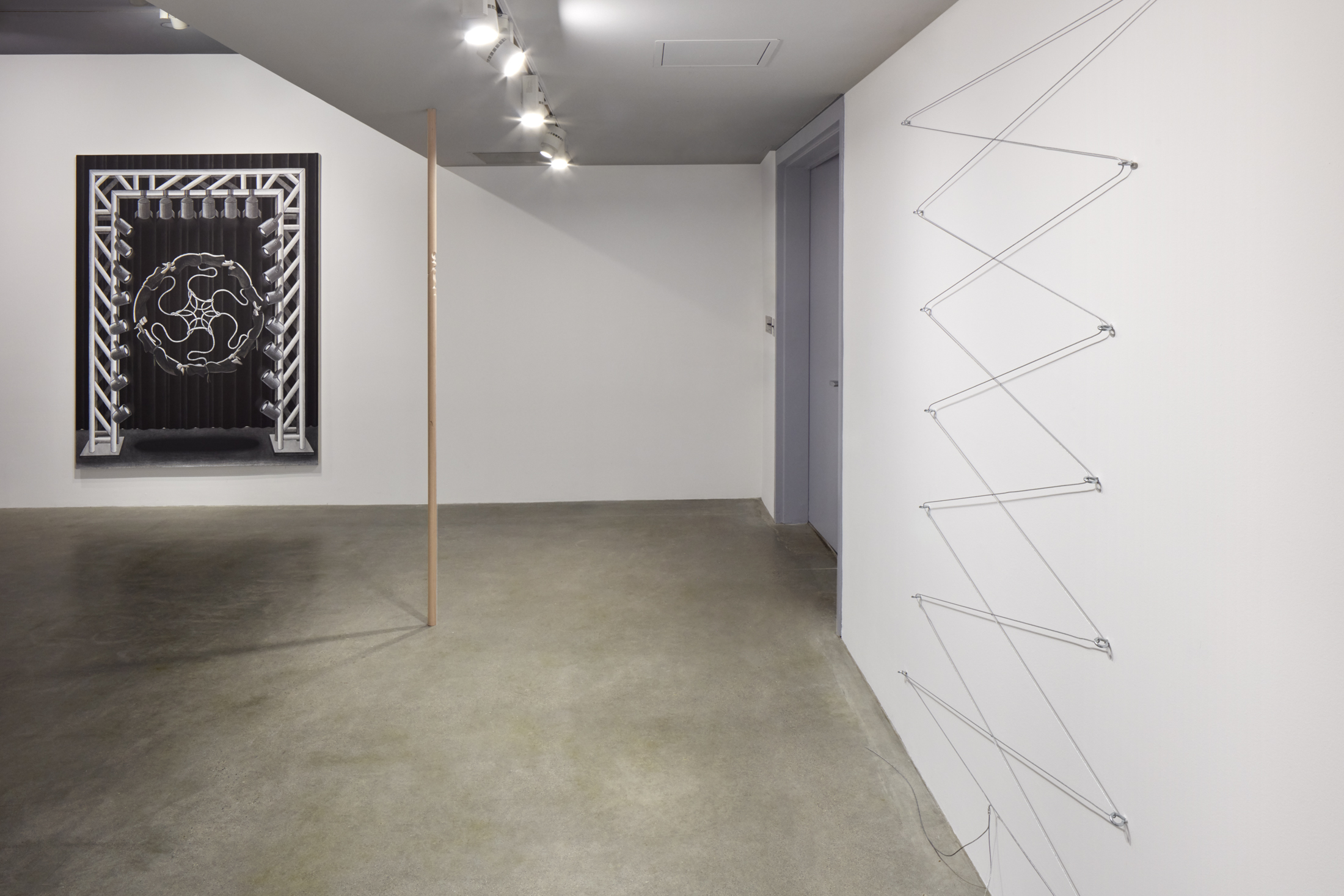 Installation view of the project space gallery with a cable zip shape on the right wall, painted stage mural at the left, and wooden pole at the center.