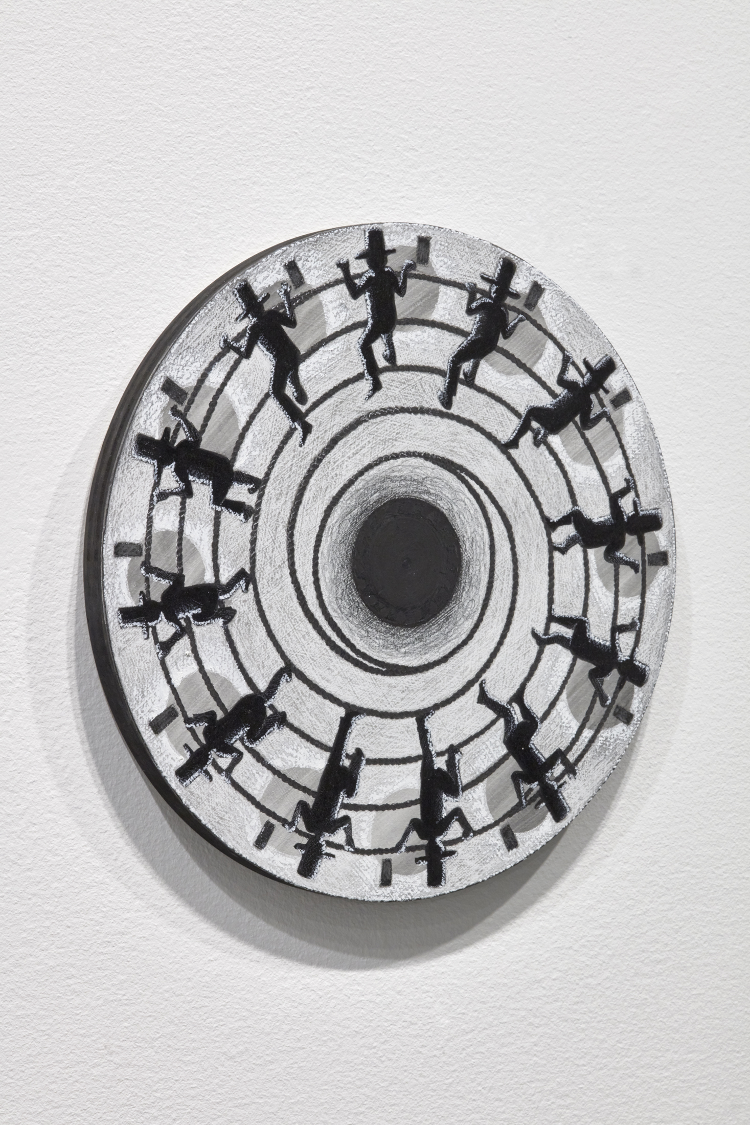 Detail side angle view of small wooden circle affixed to gallery wall with charcoal illustrations of a man wearing a tall hat climbing a rope.
