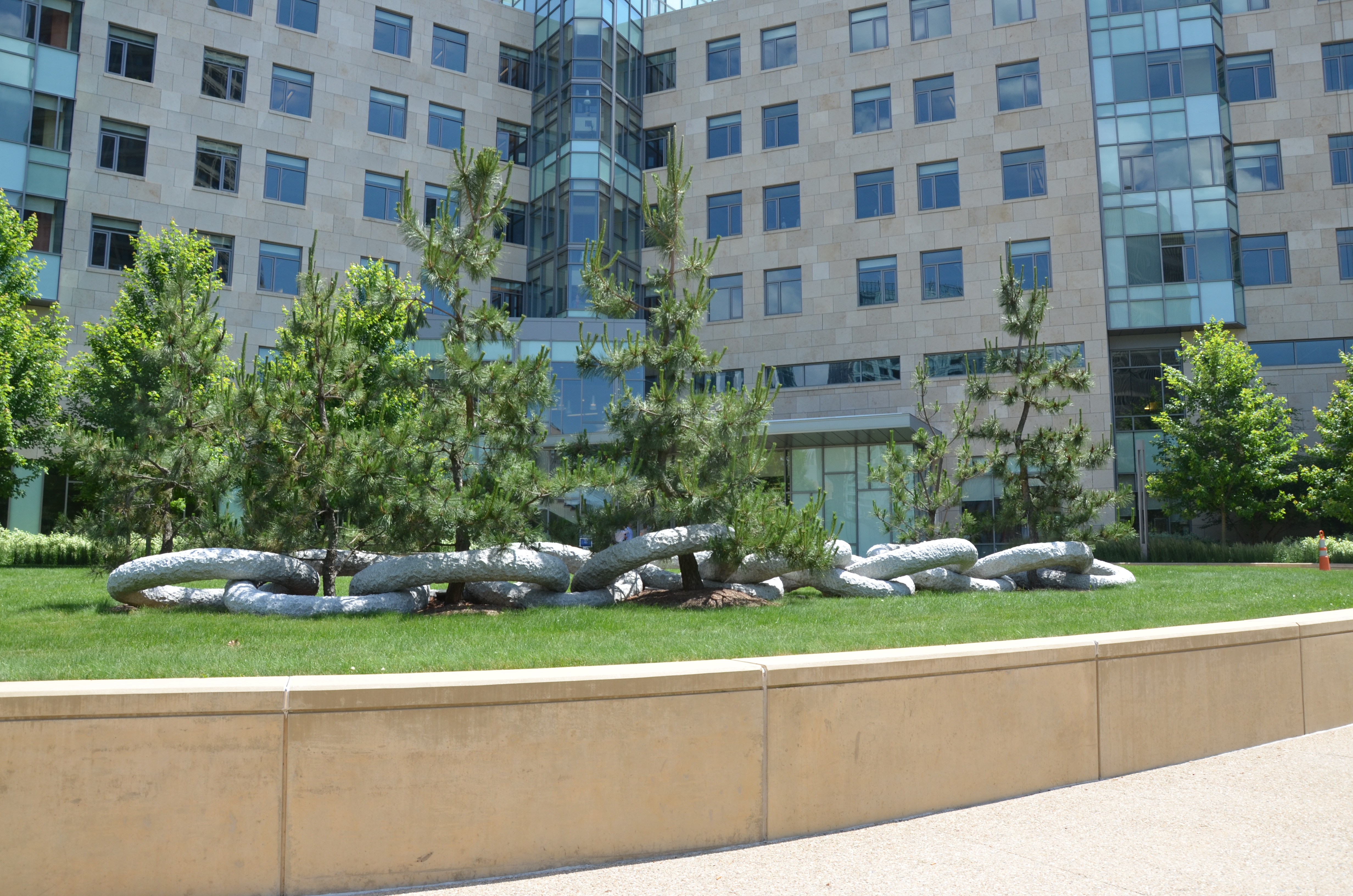 Twelve individual but indivisible granite links around trees on a garden.