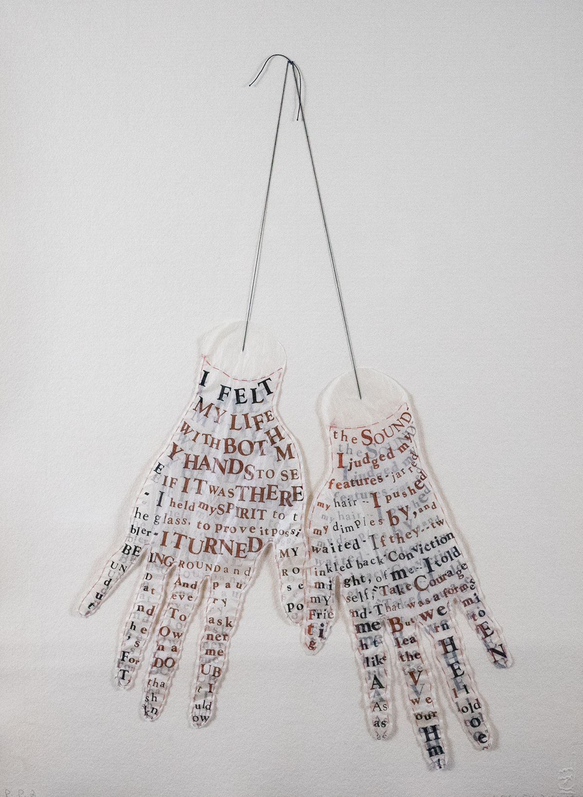 Pair of hands hanging fro ma string filled with letters and words cut out in different sizes.