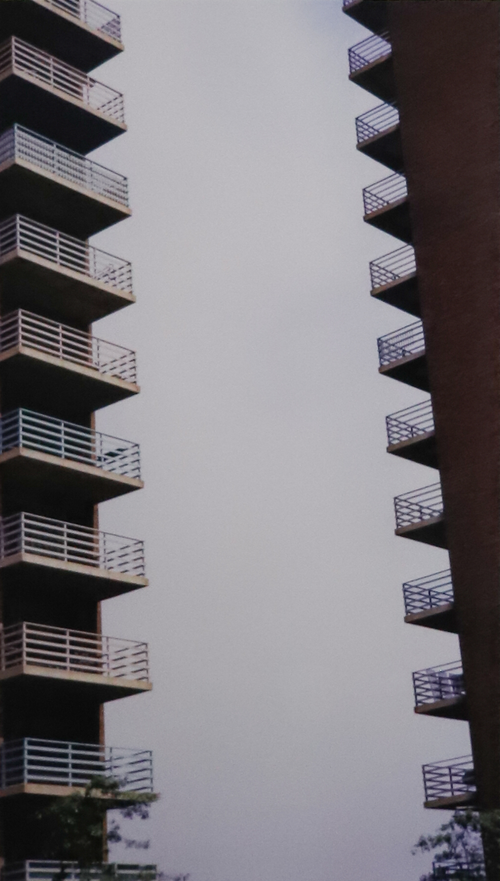 Vertical photograph of two rows of balconies on a tall housing project in new your city.