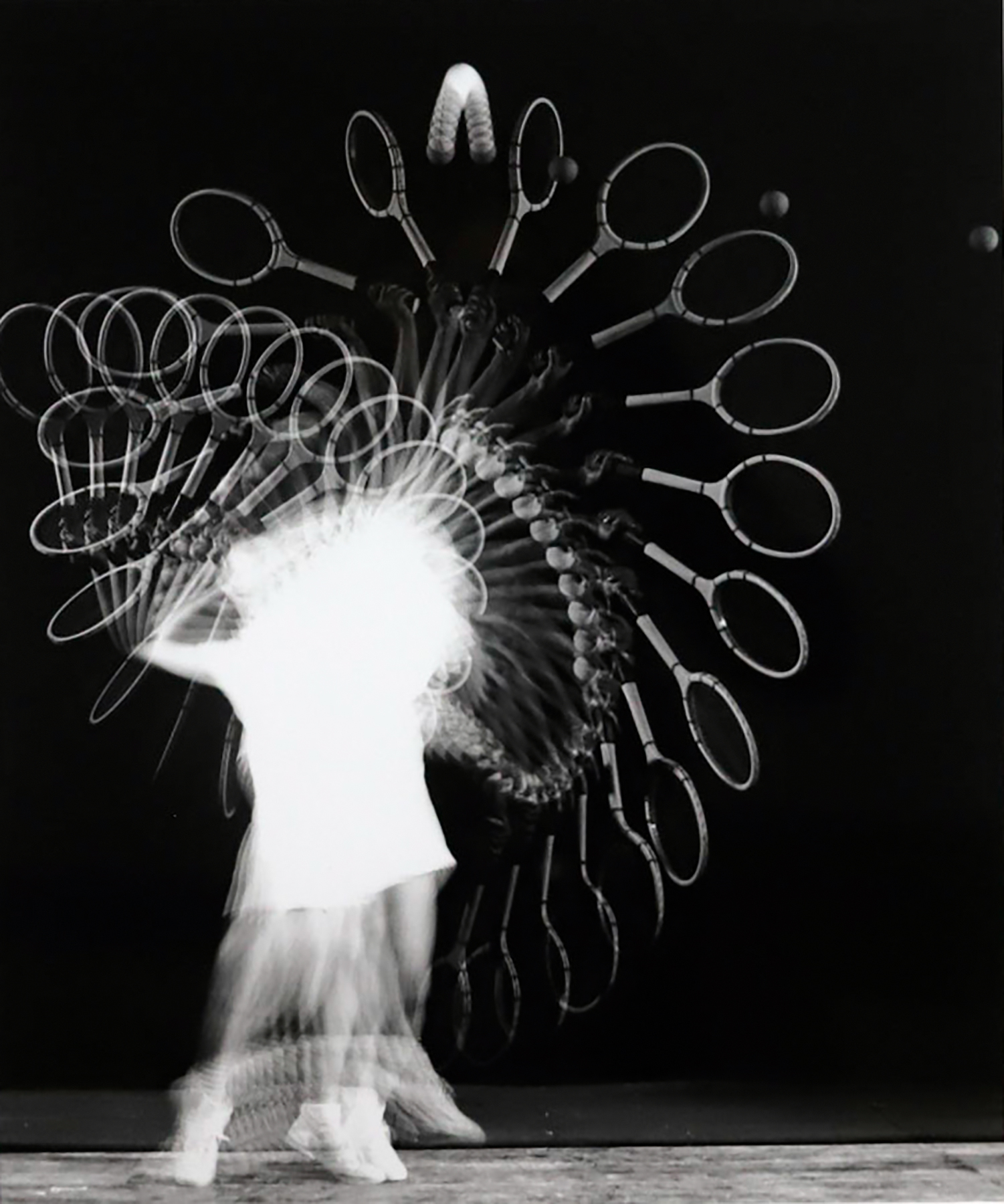 Long exposure photograph of a person hitting their tennis ball with their racket. The racket, ball, and player are in motion.