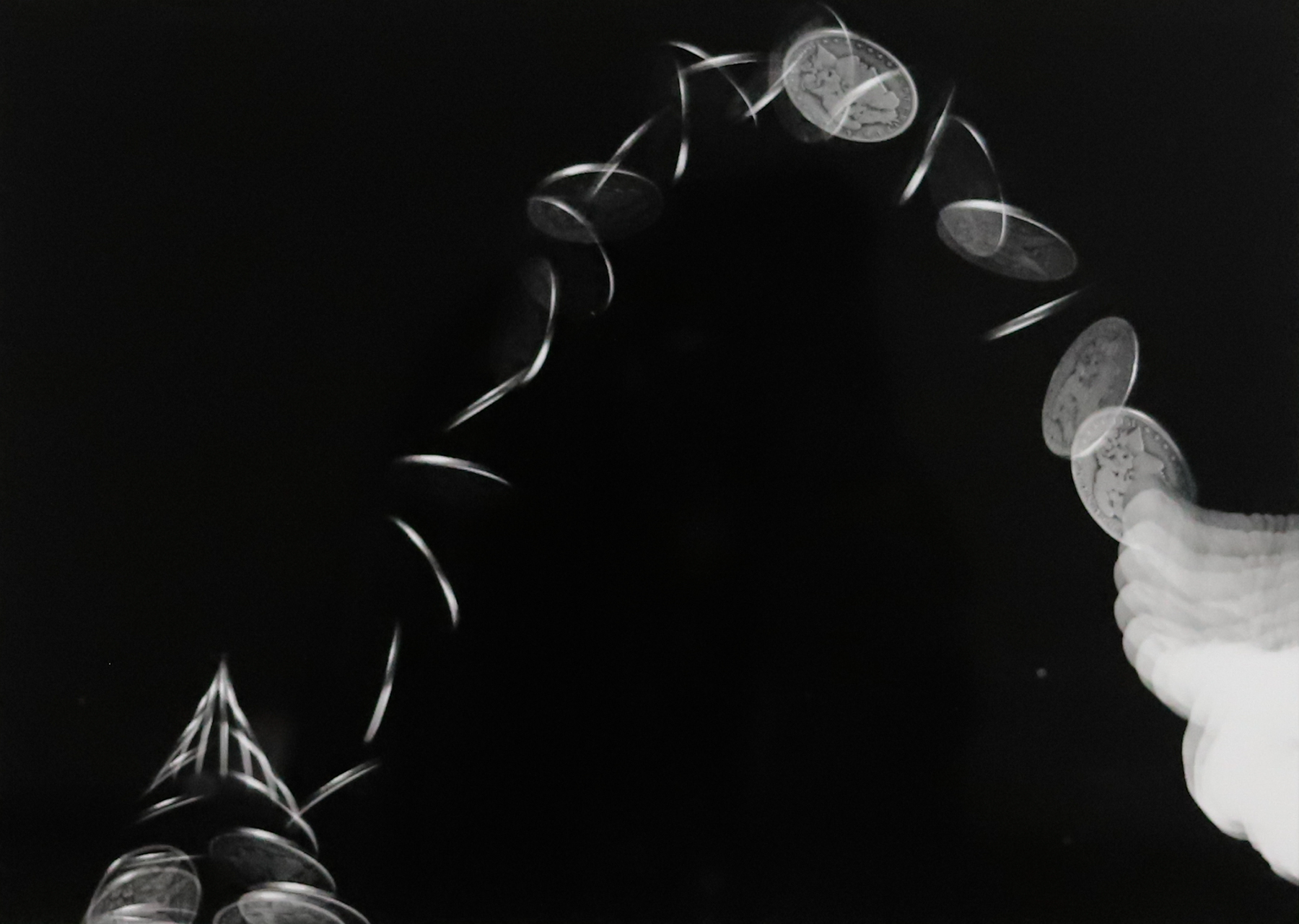 Long exposure photograph of a coin being thrown into the air.