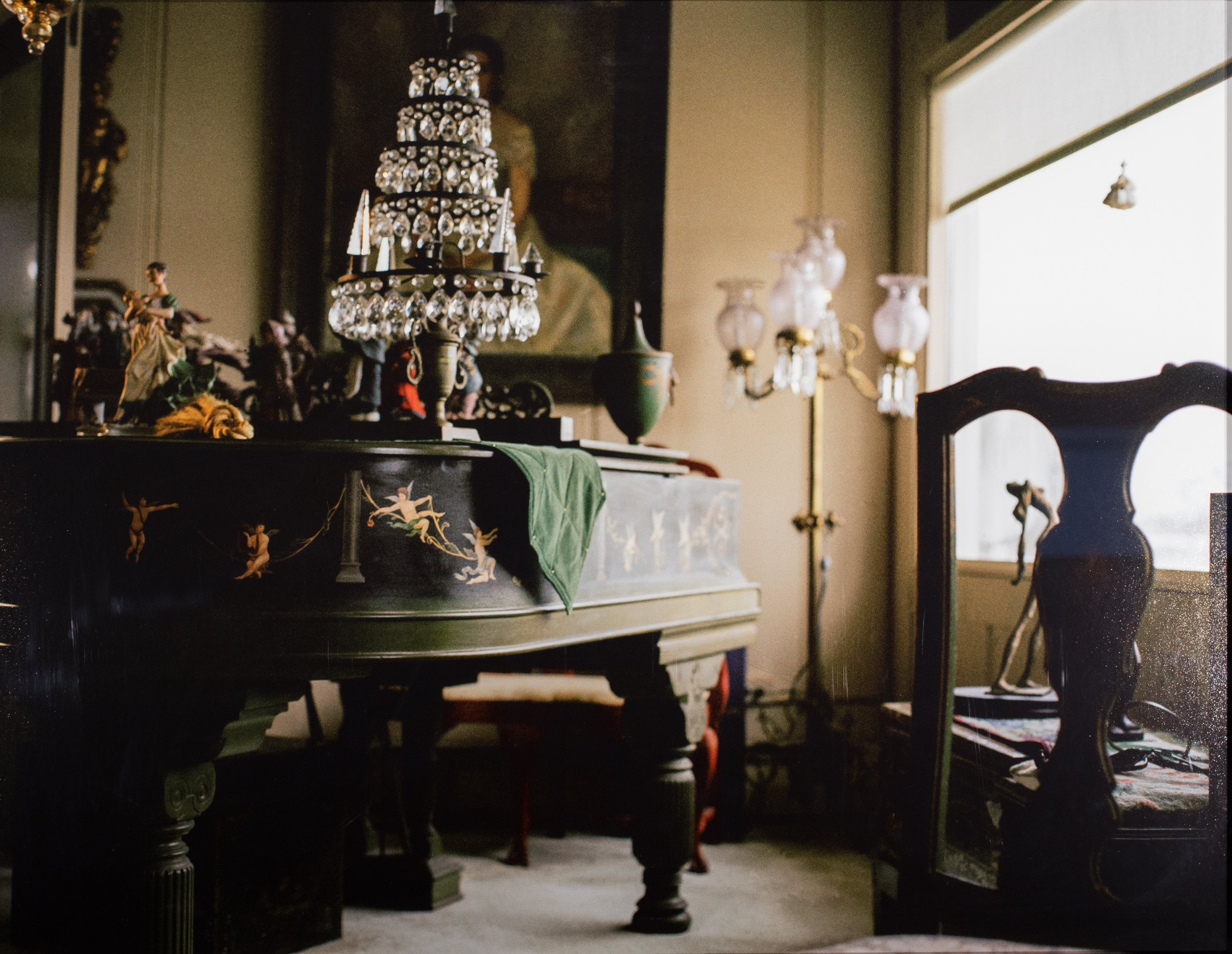 Photograph of someone's living room with a large piano and chair in the forefront and a glass Christmas tree on the piano.