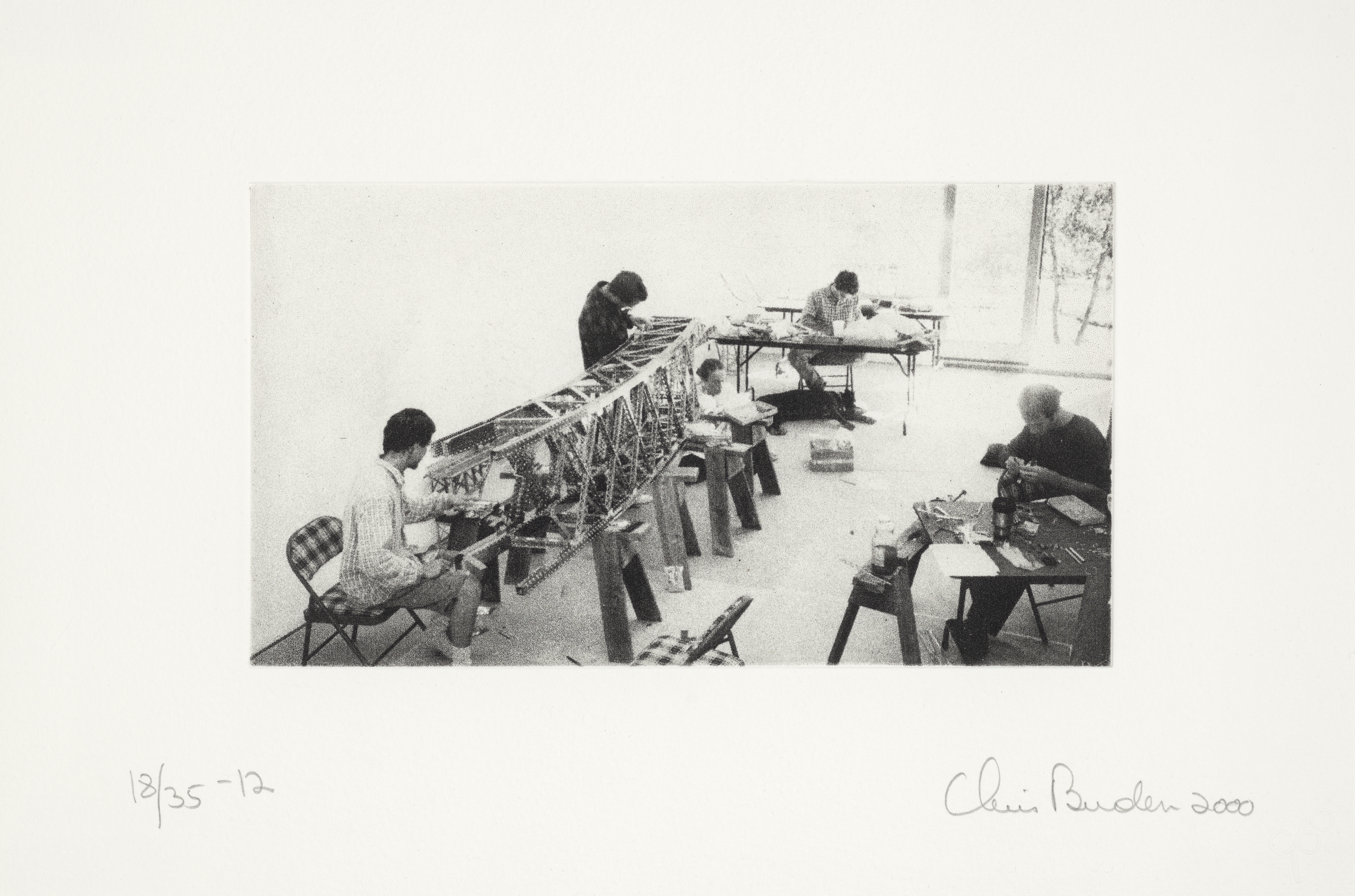 Black and white photograph of people working in a studio on a model bridge.