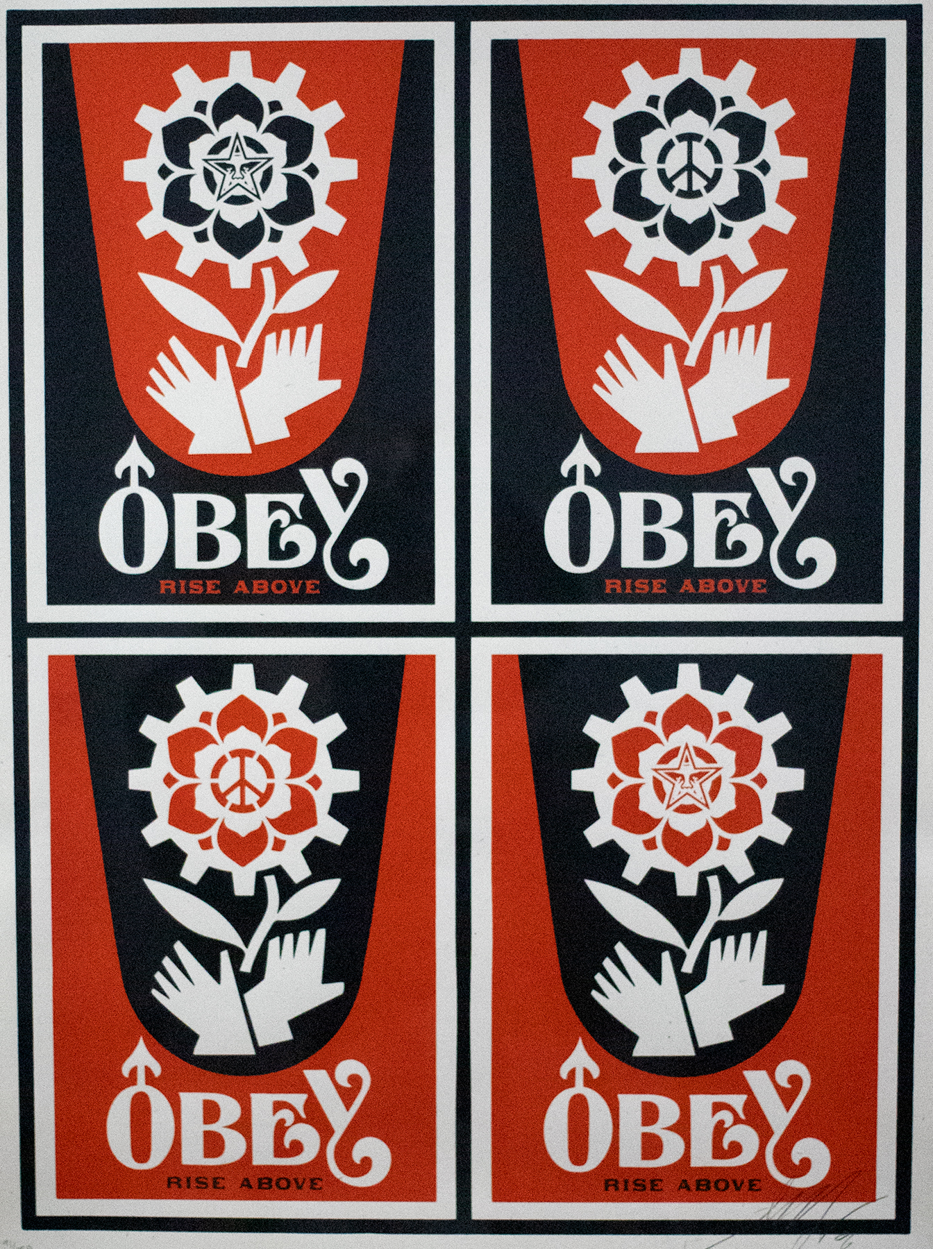 Four identical red and black stamps of a flower with hands around the stem and a peace sign in the center that reads &quot;OBEY&quot; on the bottom.