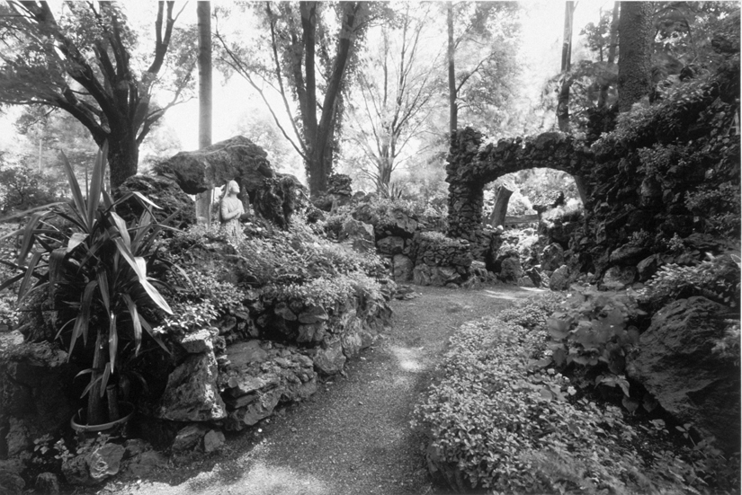 Black and white lush garden featuring stonework and a small arch.