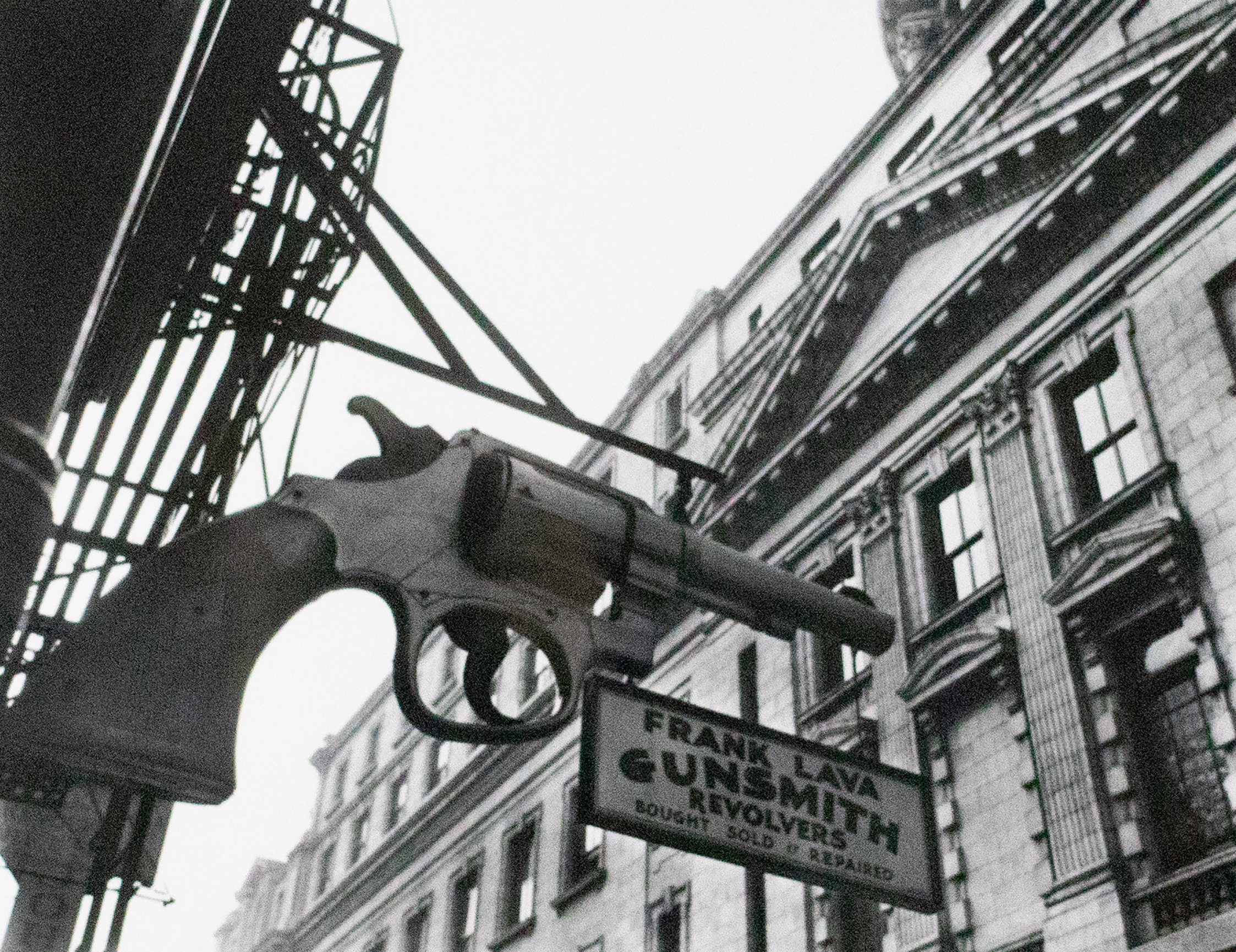 Large sign for a gunsmith featuring a huge pistol on the side of the building.