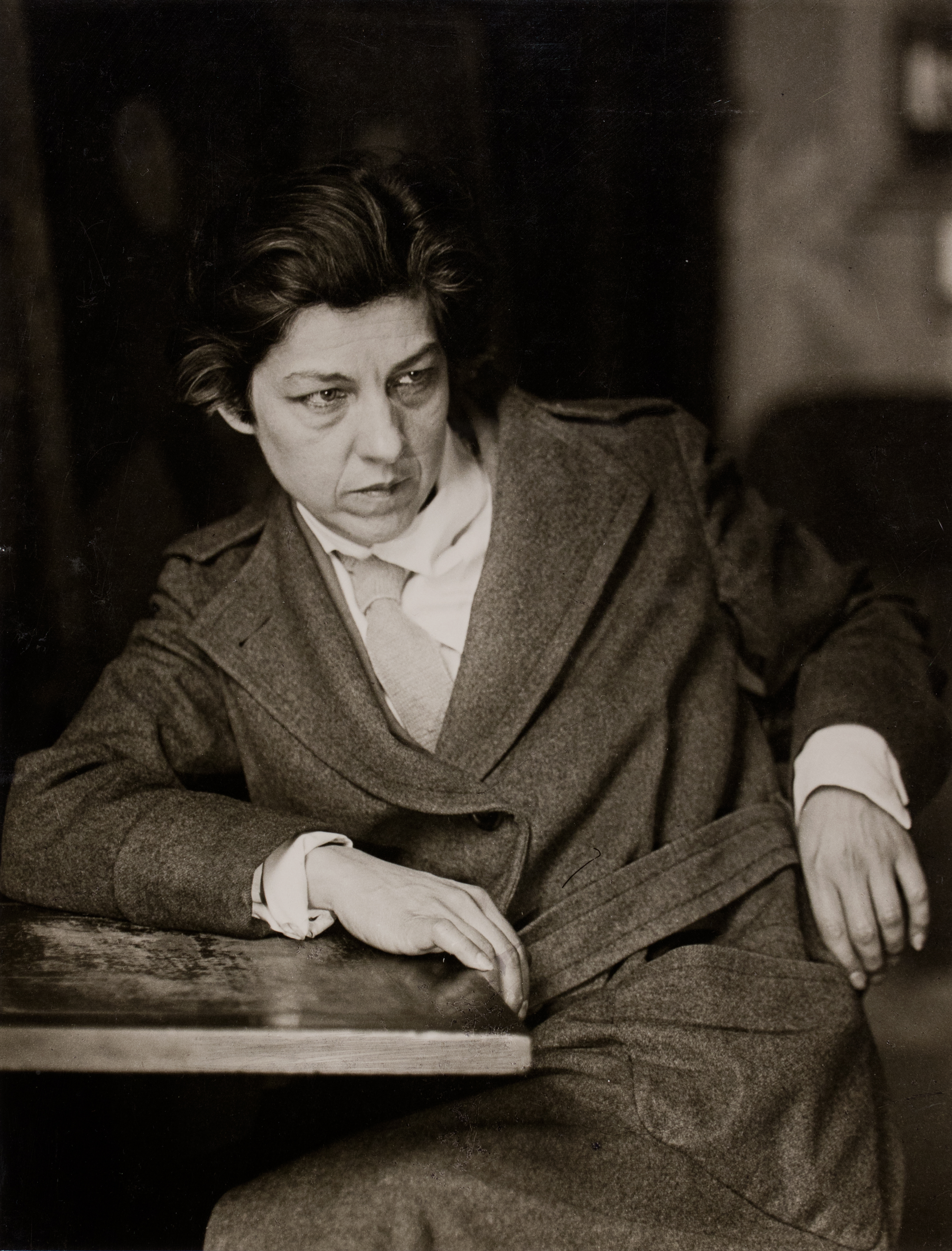 Black and white photograph of a woman sitting at a desk turning around in her chair making a confused face.