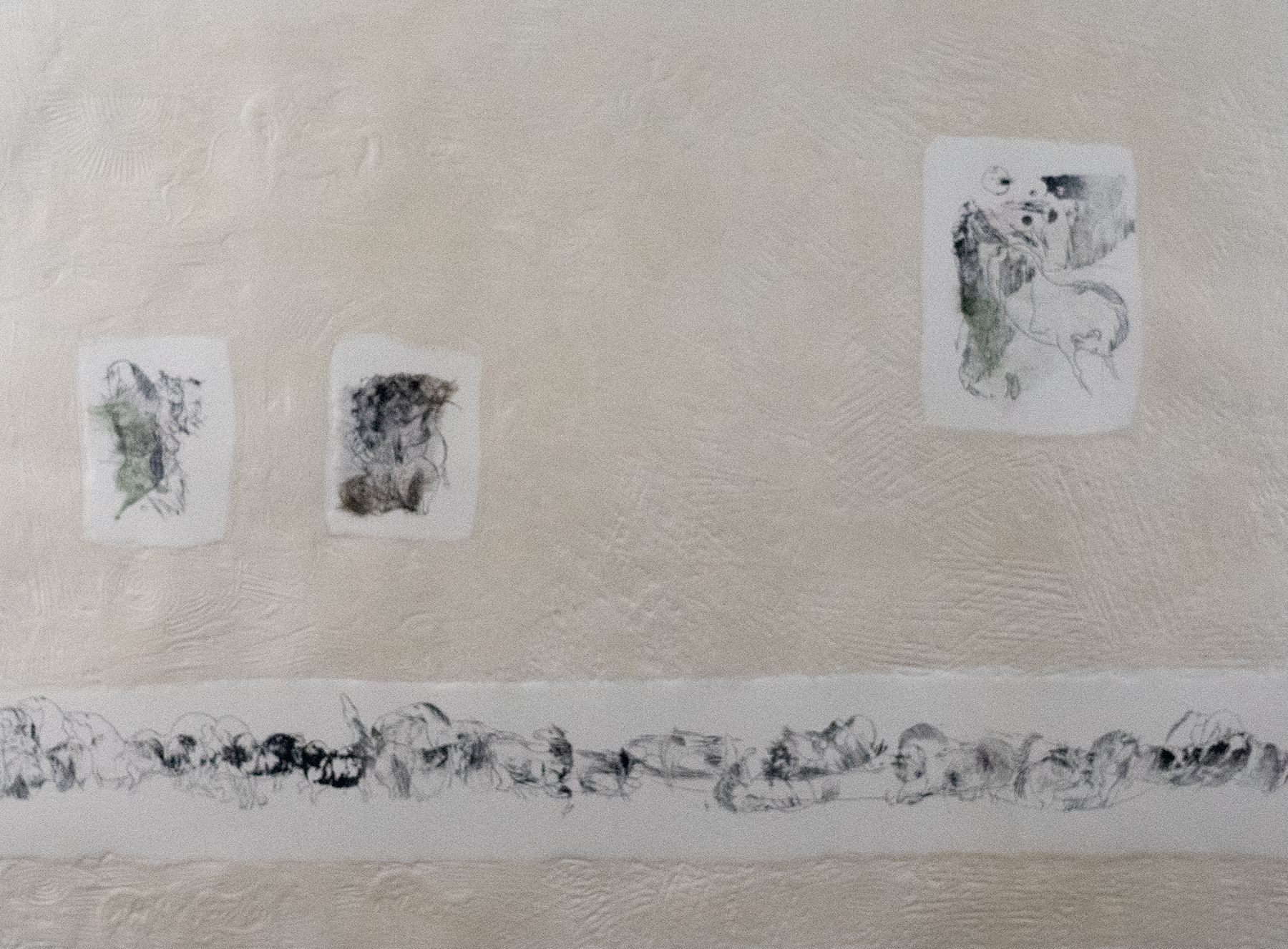 Four piece of paper cut out onto a wall with small ink blotches on each.