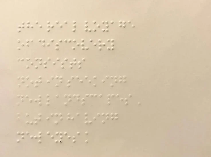Cream colored postcard with Braille writing on it.