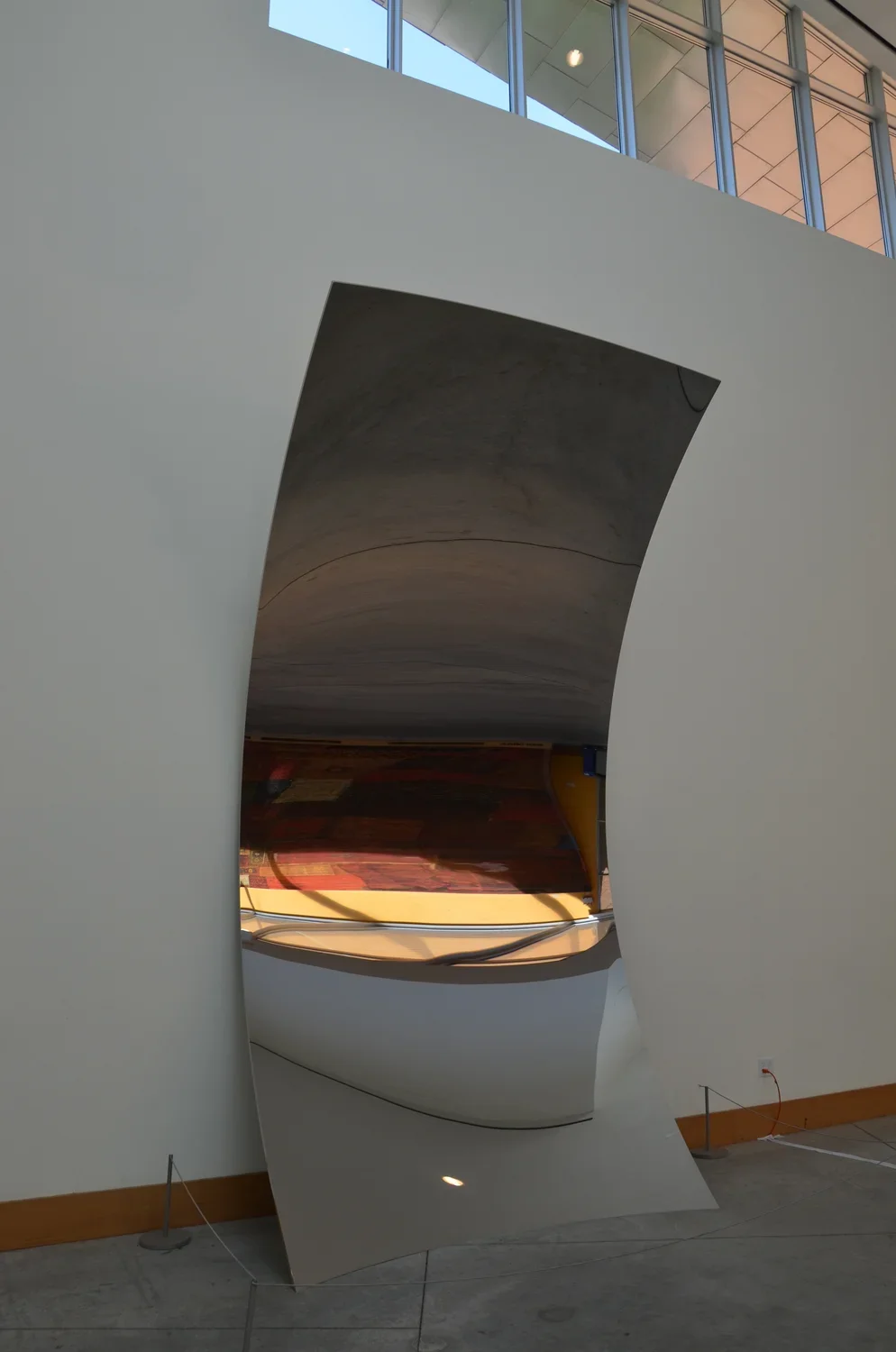 Monumental concave form which contrasts from the delicate structure, a thin sheet of mirror-polished stainless steel
