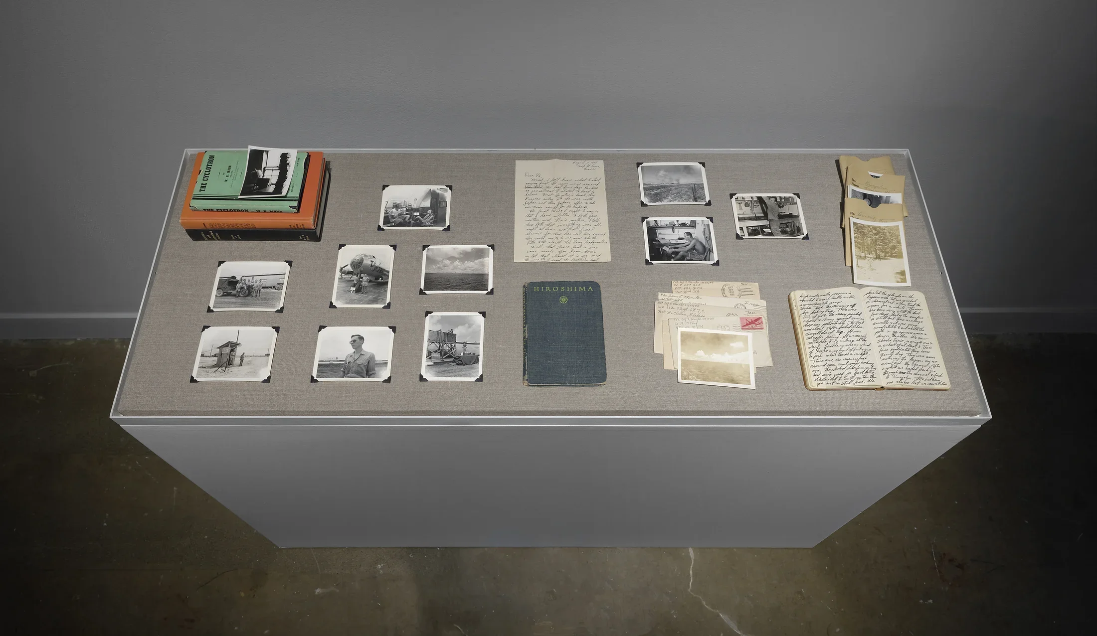 Books, postcards, letters, and photos from the Thornton family archives are arranged on a grey vitrine.