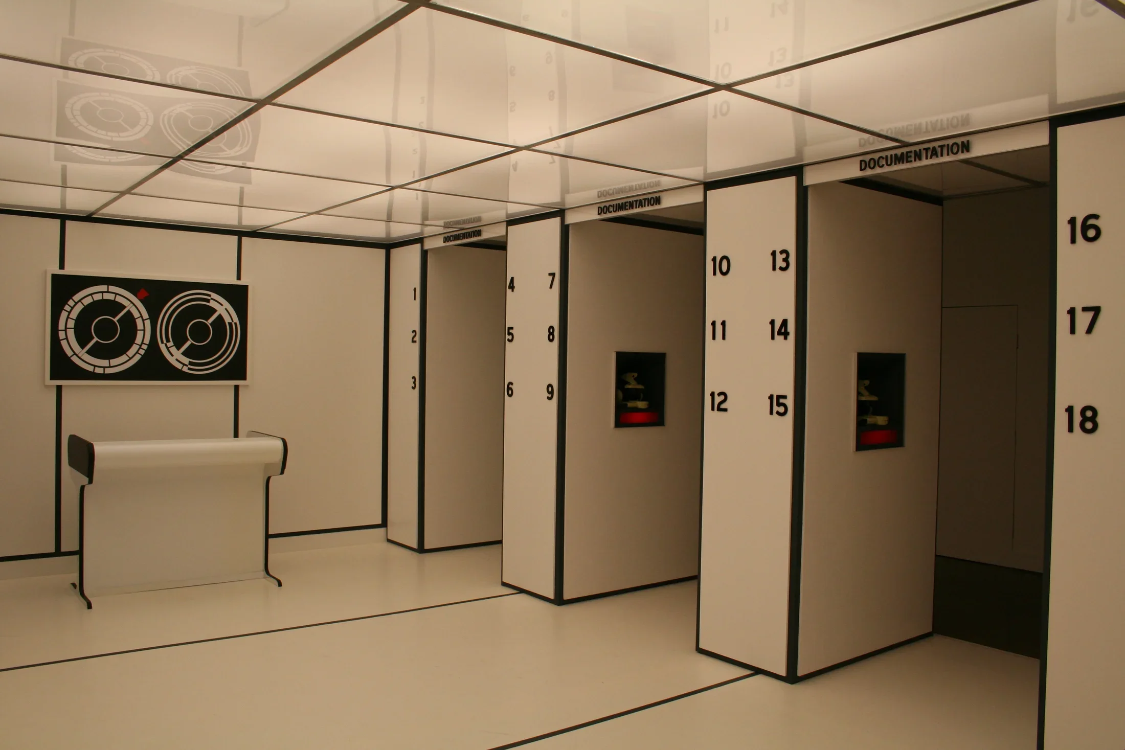 Installation view of a modern white room with black borders and numbers lining the right wall.
