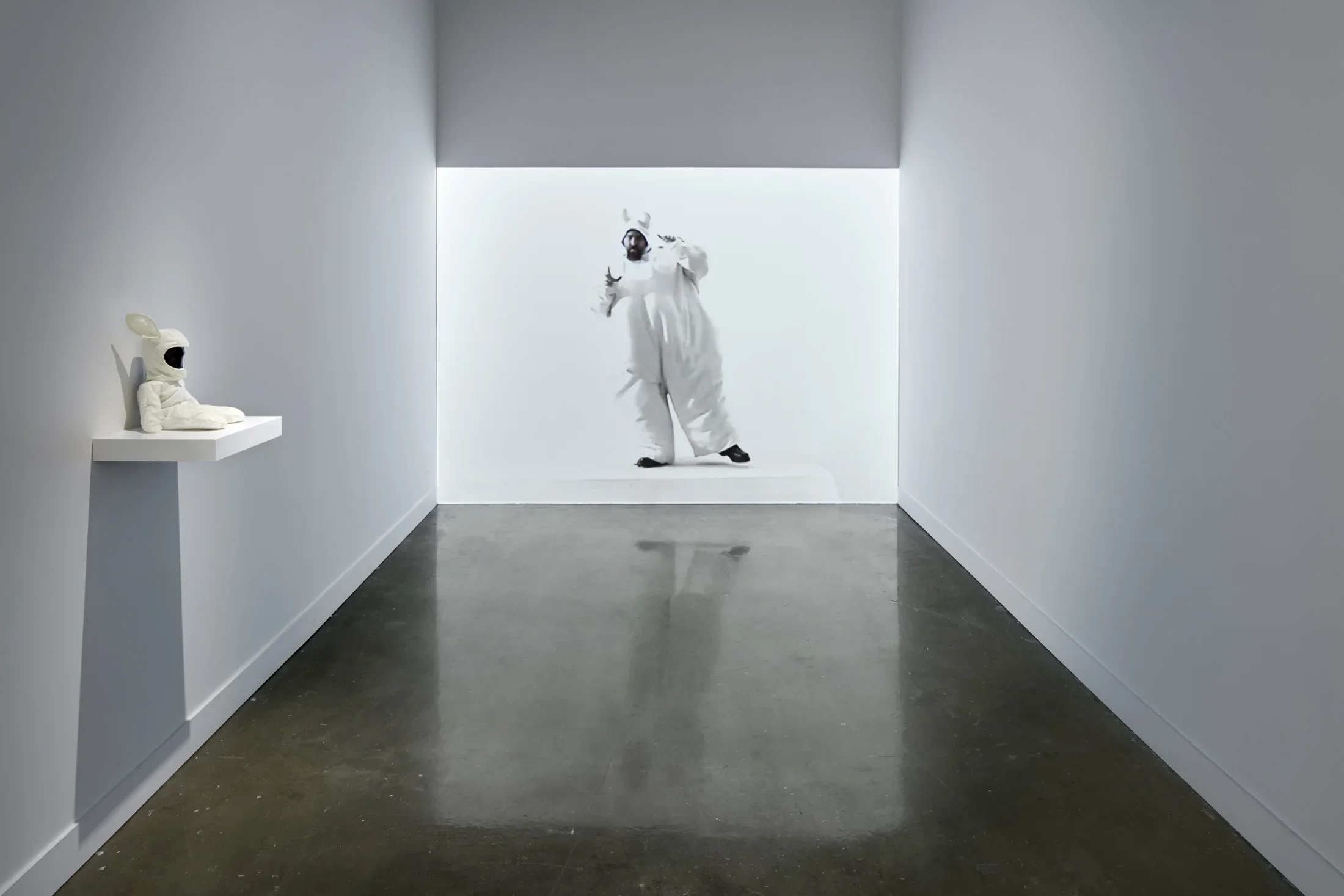 Image of a person in a bunny costume projected onto a gallery wall. 