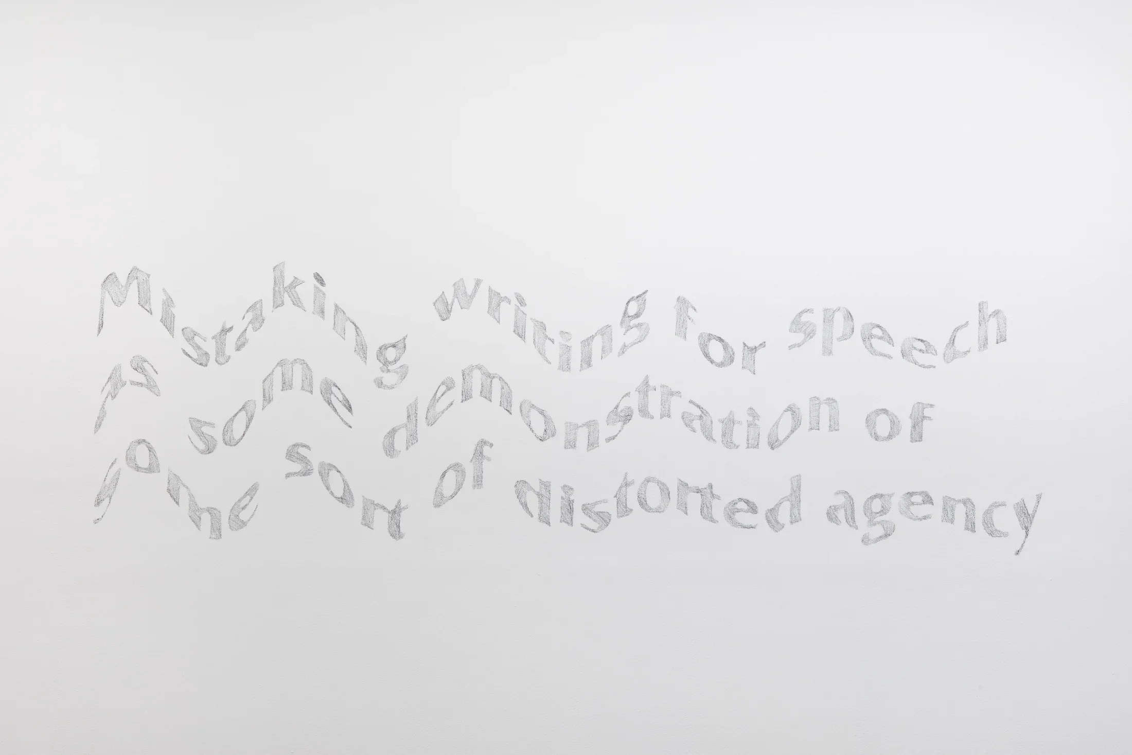 White gallery wall with a mural that has three lines of gray, wavy looking text.