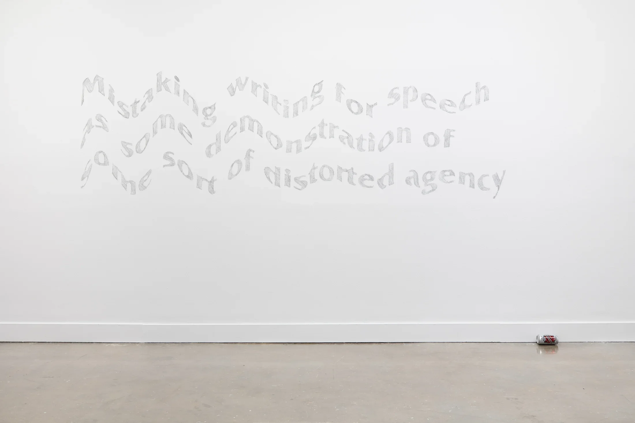 Mural featuring three lines of gray, wavy looking text on a white gallery wall with a beer can lying on its side below and slightly to the right of the mural. 