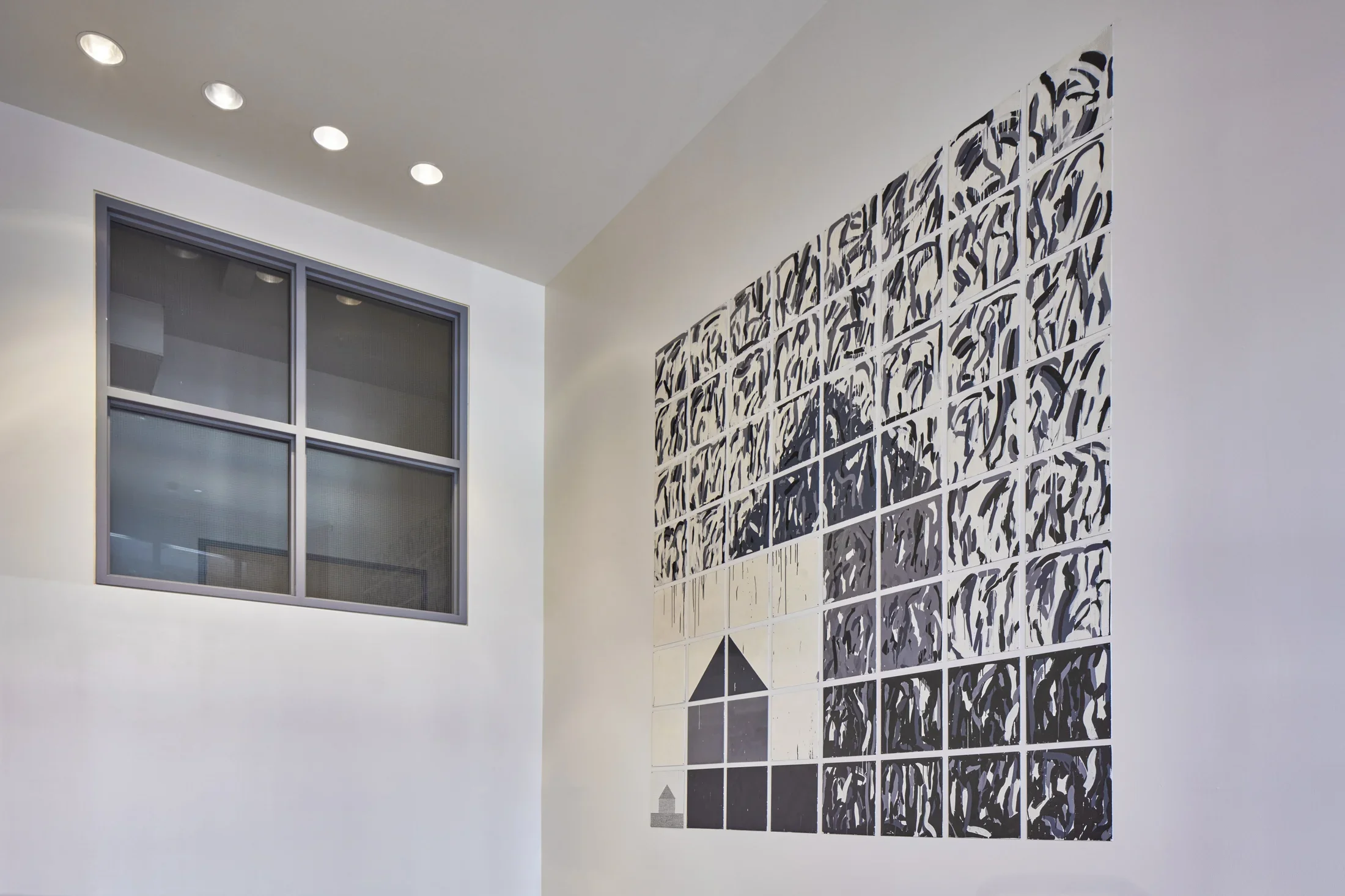 Rectangular artwork with tile like qualities and geometric shapes that resemble the shape of a house.