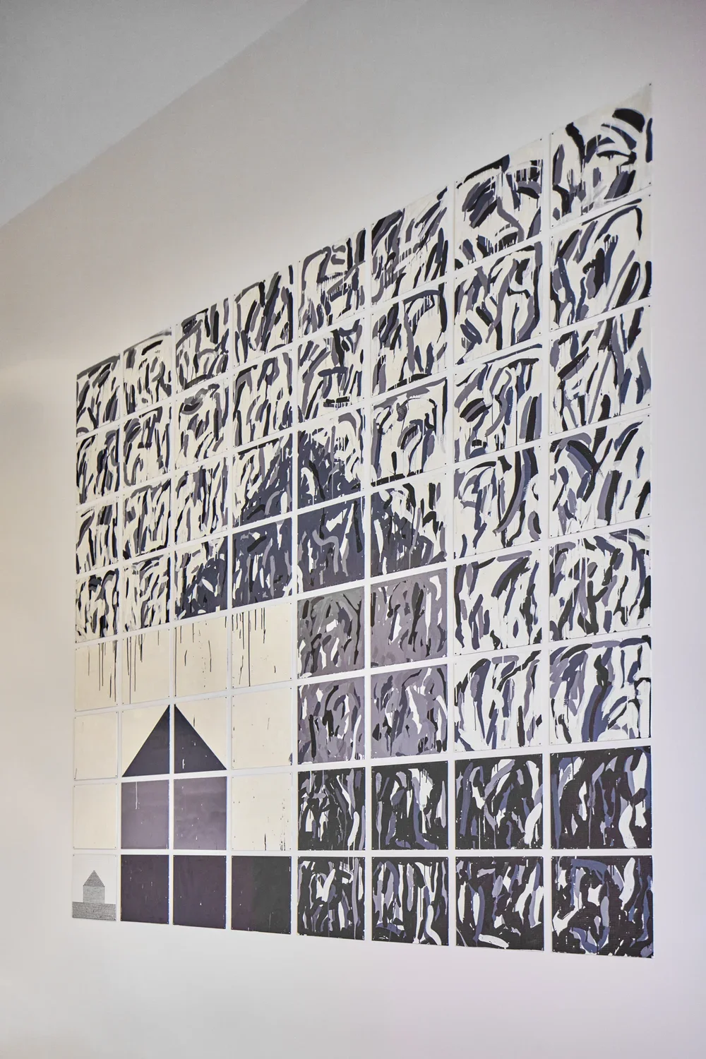 Rectangular artwork with tile like qualities and geometric shapes that resemble the shape of a house.