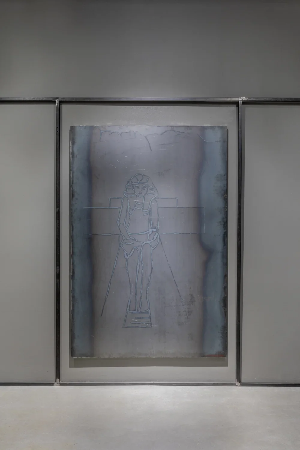 A large, vertical welded steel drawing hanging in the center of a wall in between two vertical steel bars and one horizontal bar above.