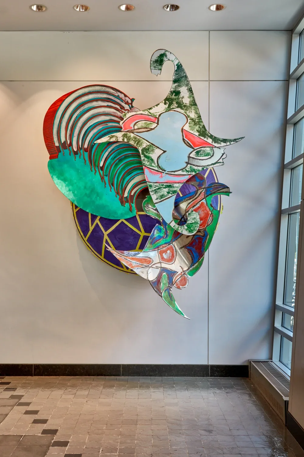Colorful sculpture made of acrylic and enamel on aluminum hung on a white wall. 