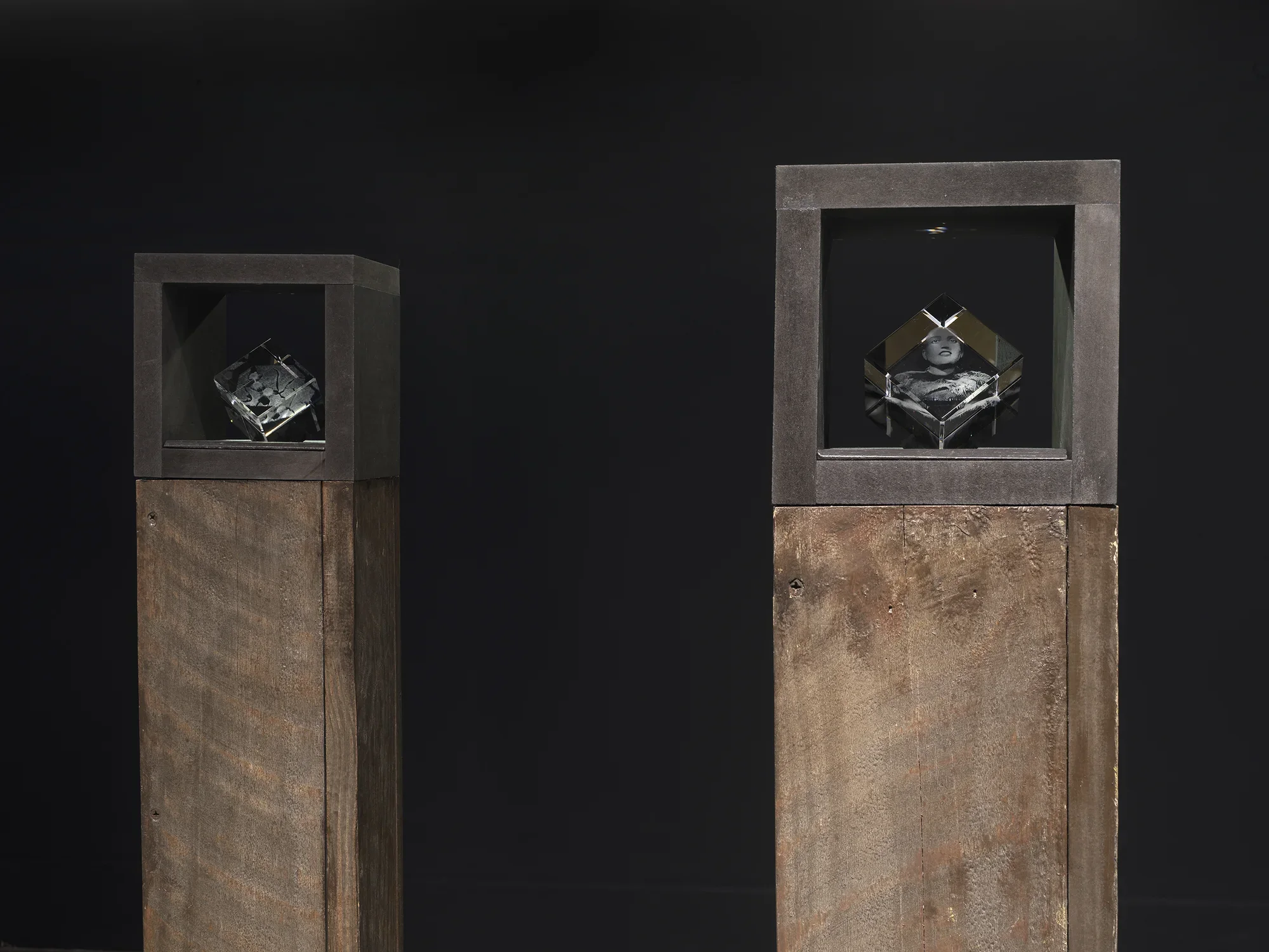 Small laser-cut glass cube sculptures nested inside the top section of brown pedestals.