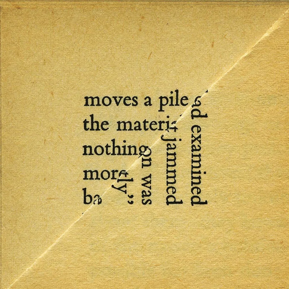 Image of a tan square piece of paper with black text. The paper in the front is folded in half diagonally to the bottom right. The text on the partly covered paper reads "moves a pile the materi nothing more b" and text on the folded paper reads "ad examined jammed on was ly"