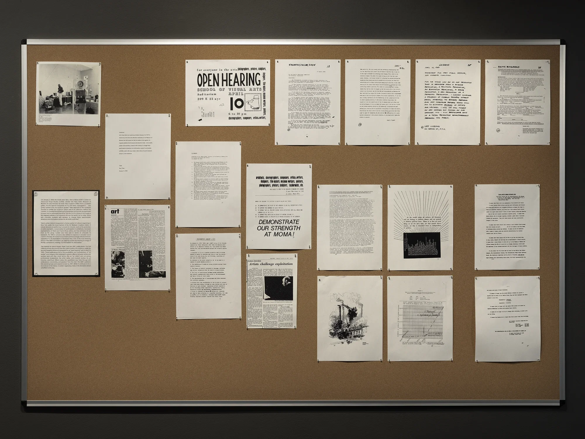 A bulletin board is covered with grayscale documents, mostly letter-sized and covered in text. The largest text is on a flier announcing an “open hearing” at the School of Visual Arts. Another flier enjoins “architects, choreographers … critics, writers, designers” and others to “DEMONSTRATE OUR STRENGTH AT MOMA!”