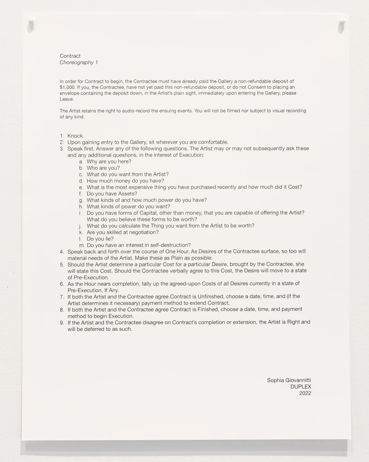 A document titled 'Contract Choreography 1,’ printed on white paper with black text, is pinned to a wall. The text is formatted with numbered bullet points, appearing as a set of instructions and questions for discussion.