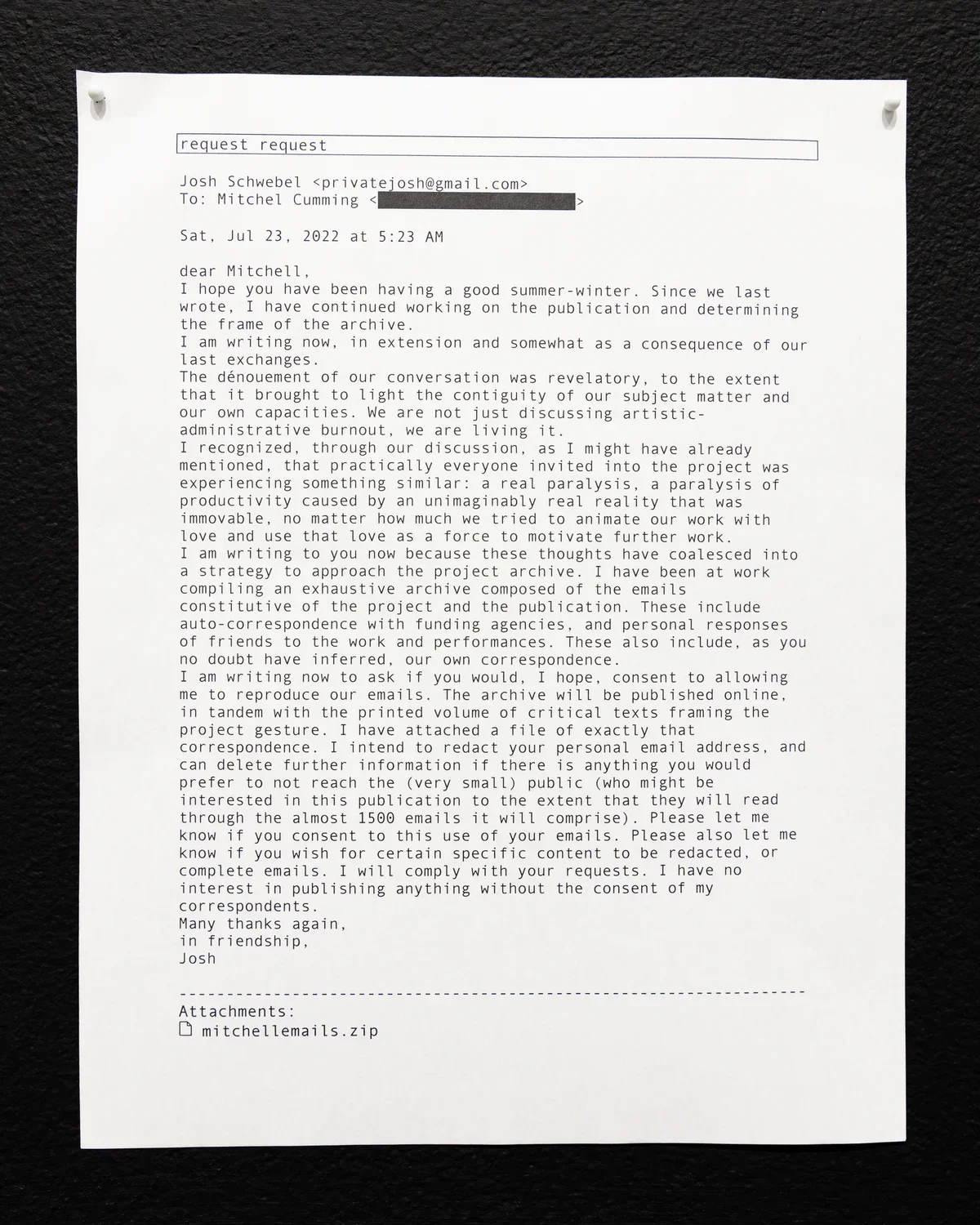 A printout of an email on white paper, secured to a dark surface with two pushpins. The email, dated July 23, 2022, is from Josh Schwebel to Mitchel Cumming discussing a project archive, burnout in the art sector, and a request to reproduce their email correspondence for the archive.
