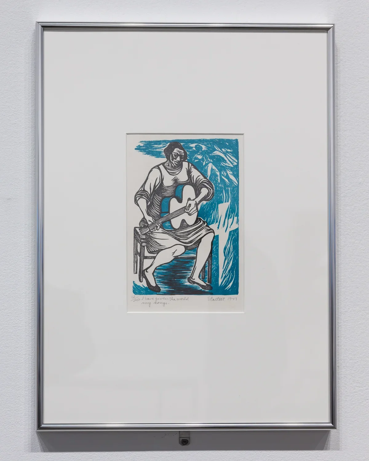 A framed print hanging on a wall shows a Black woman—rendered mostly in black ink—seated in a chair playing guitar. To her right, two images emerge from a swirling blue background: a hooded figure leans forward to assail another figure, and flames shoot upwards from a cross.