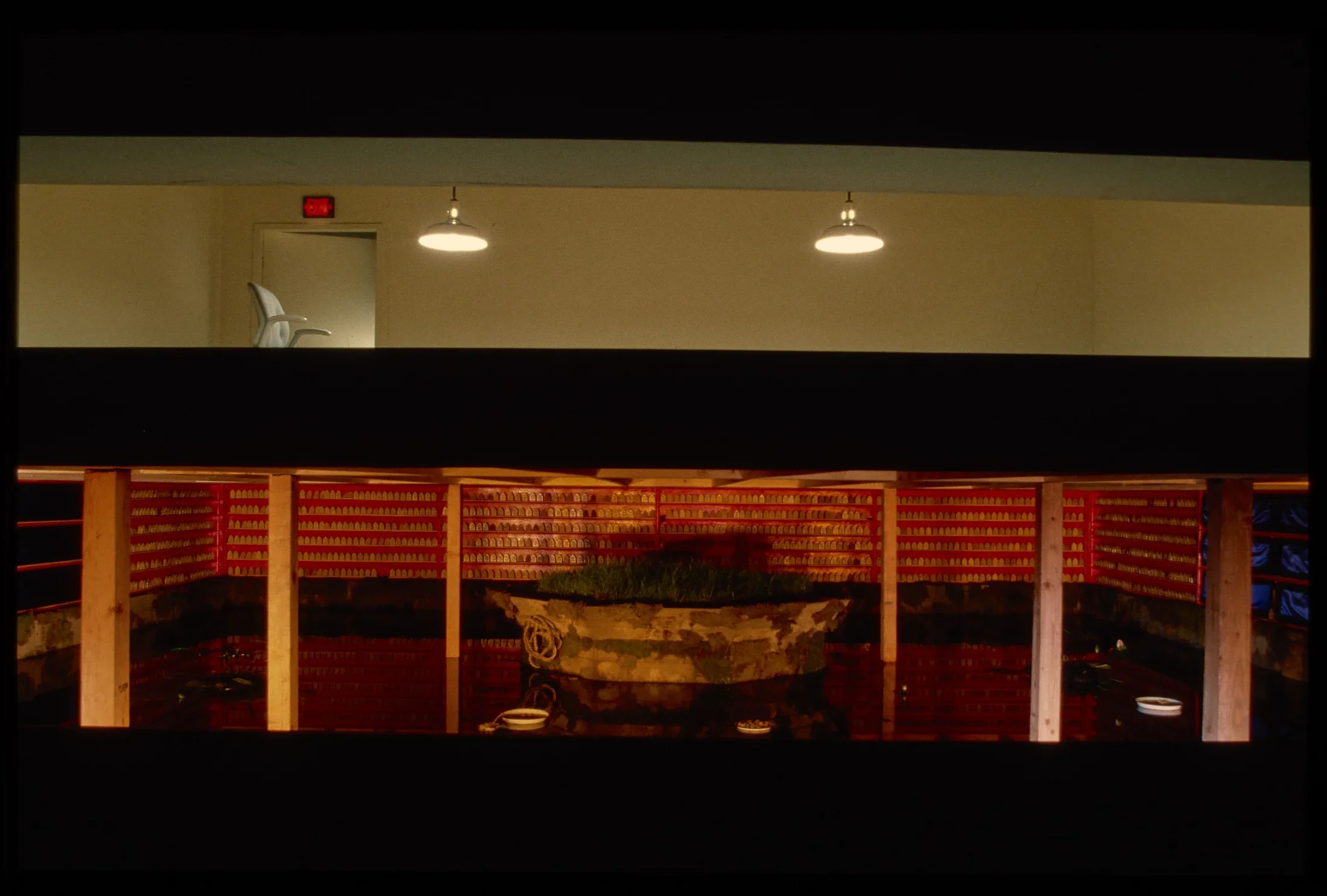 The gallery is split above and below. The top floor has a chair and two hanging lamps. The bottom is a warmly lit pond.