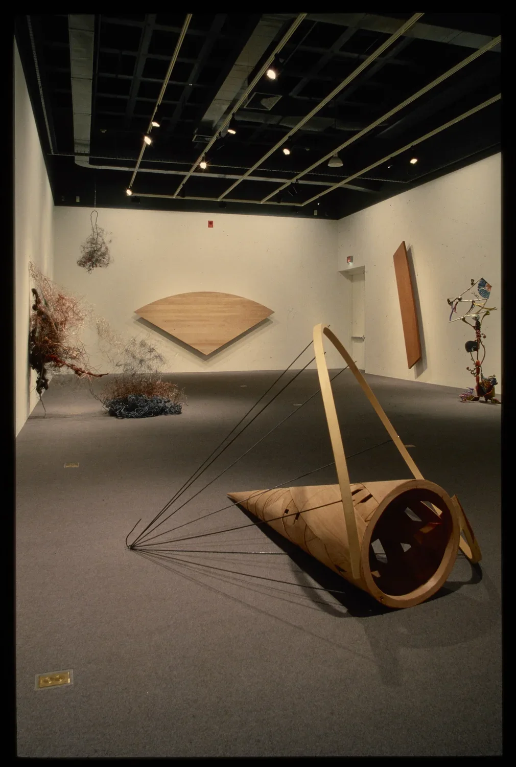 Organically shaped sculptures hang from the ceiling and walls. Each sculpture is spotlit, creating shadows on the floor.