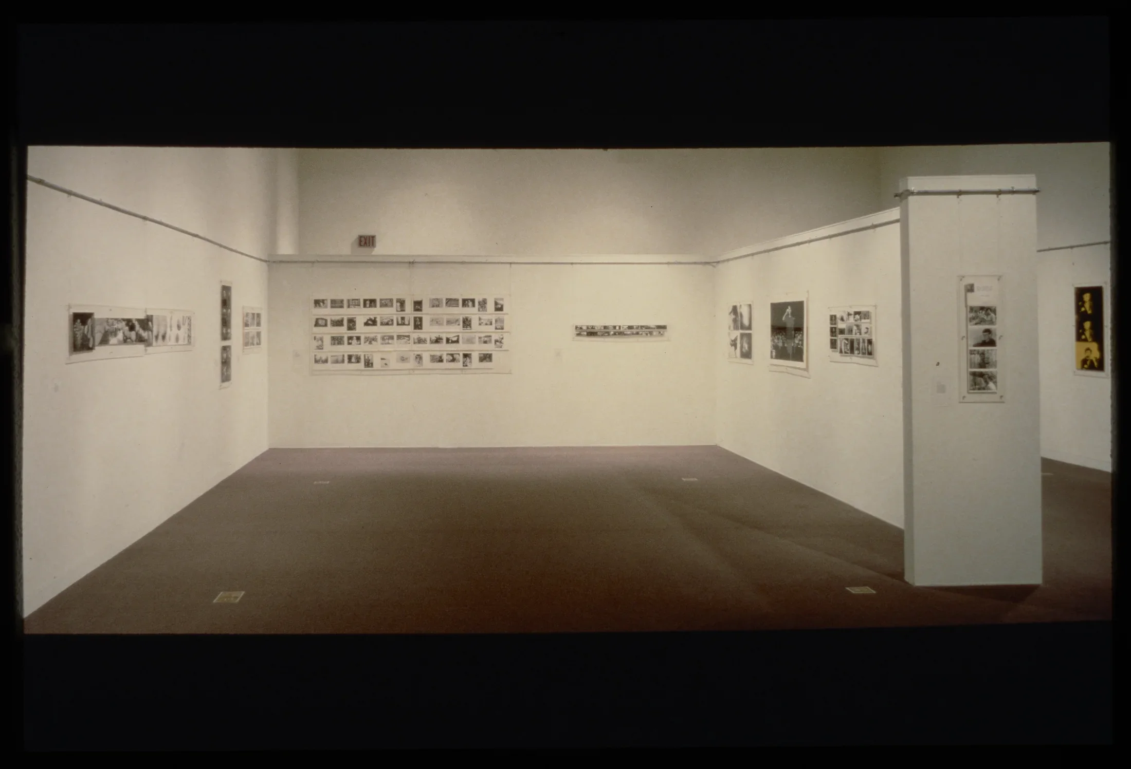 Groupings of black and white photos of varying sizes line the walls of a gallery.