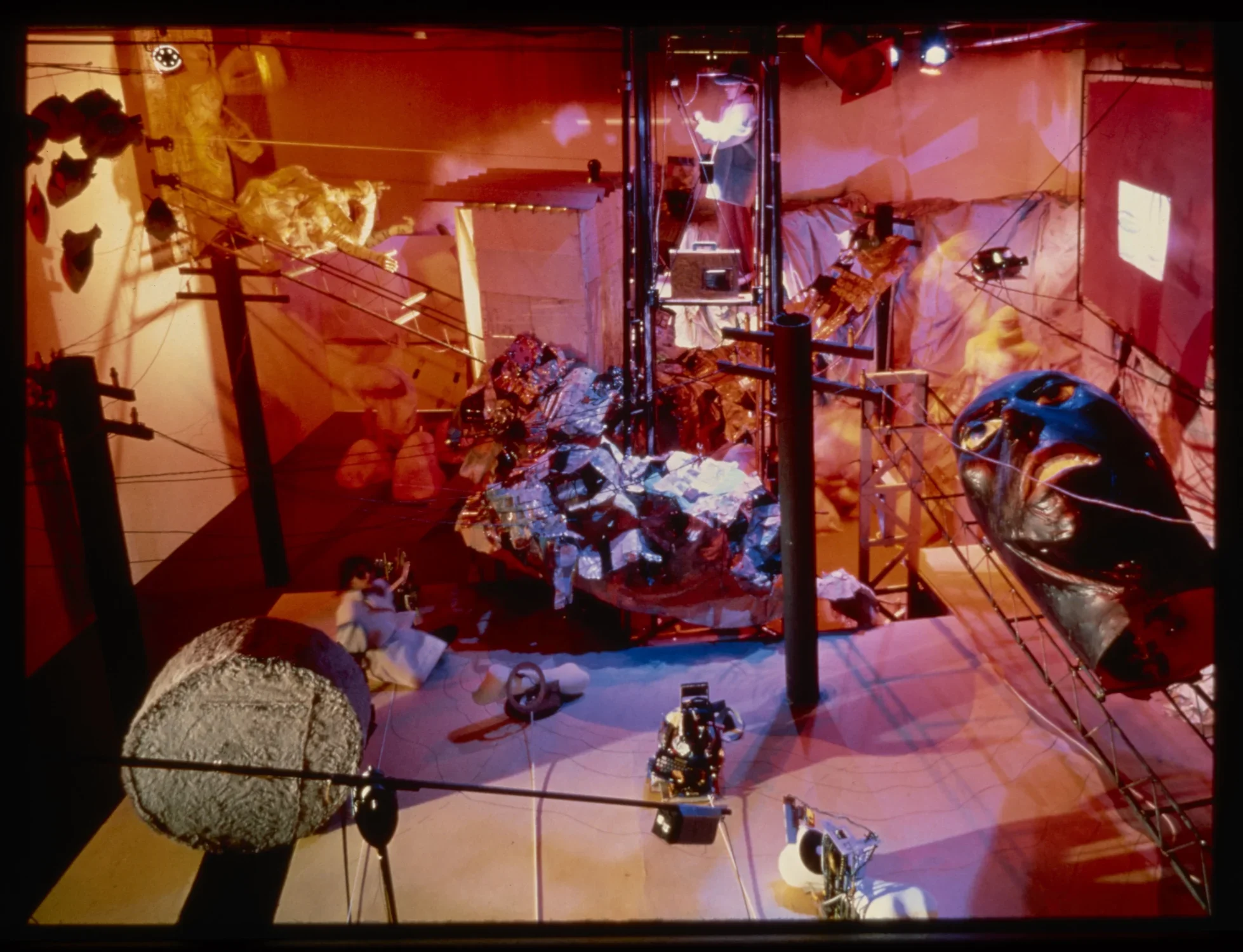 View from above of an environmental installation of an abstract mechanical landscape. A person sits in the middle of the installation.
